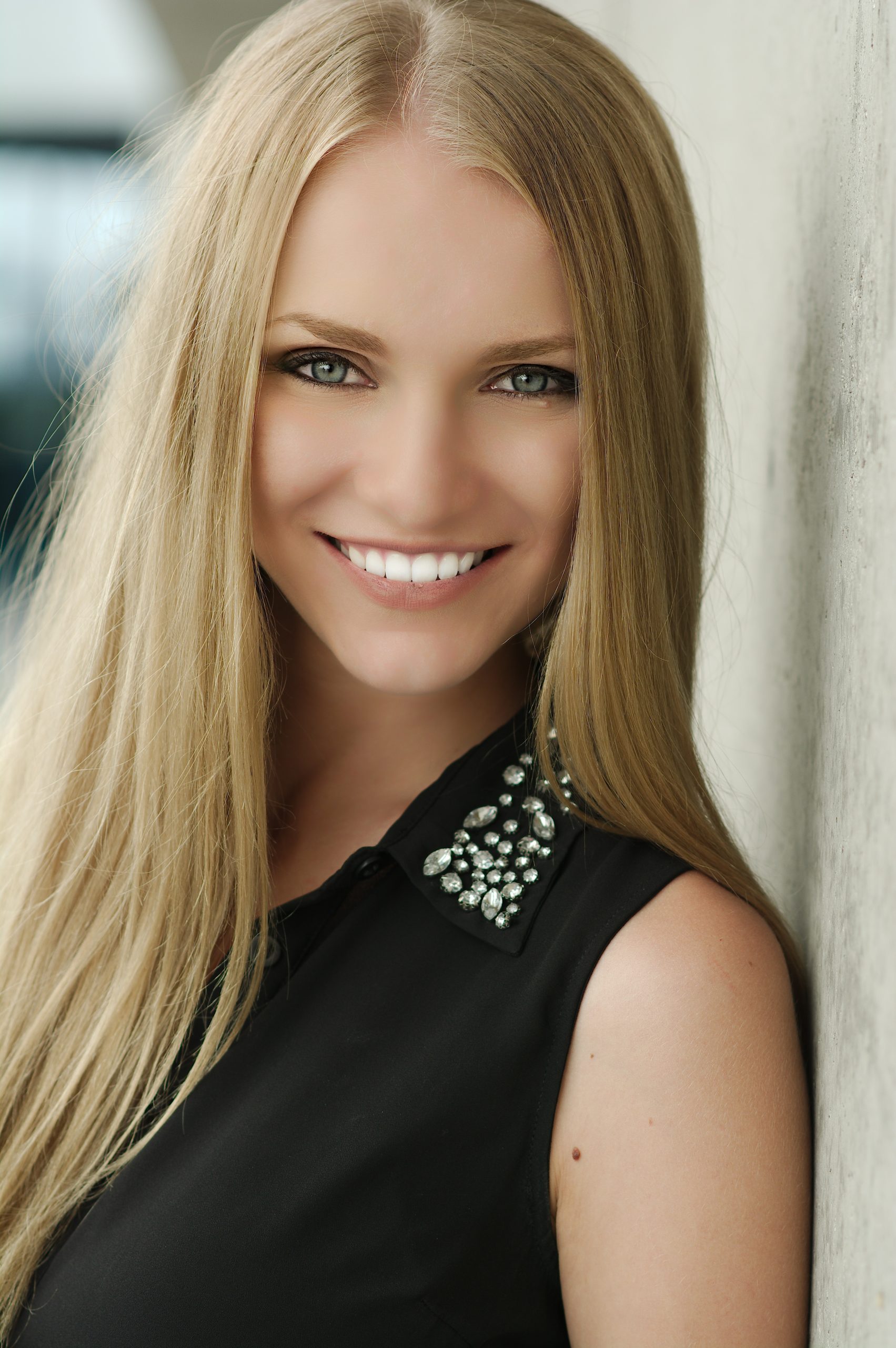 Smiling woman with long blonde hair wearing a jeweled black top