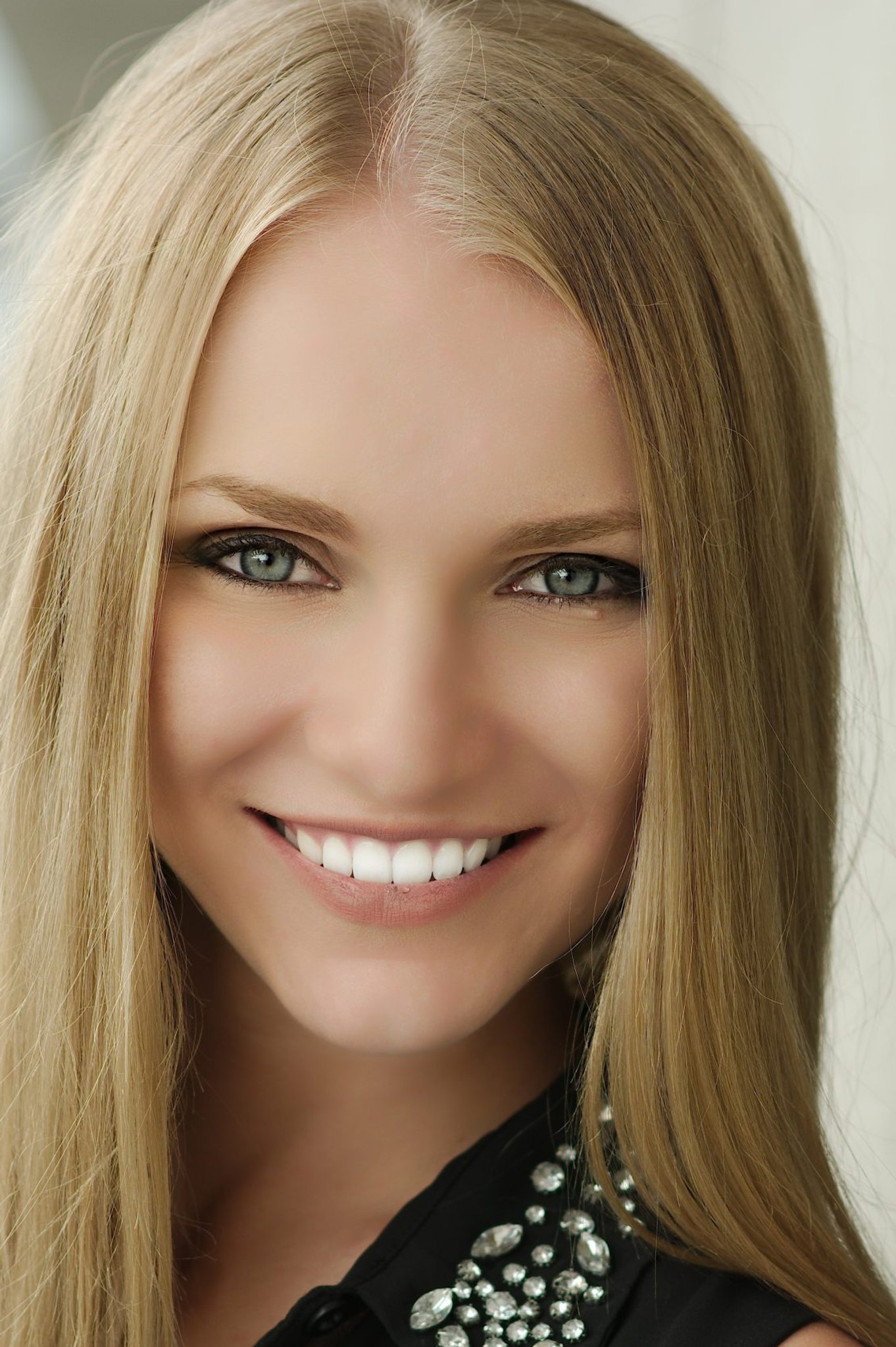 Smiling woman with long blonde hair wearing a jeweled black top