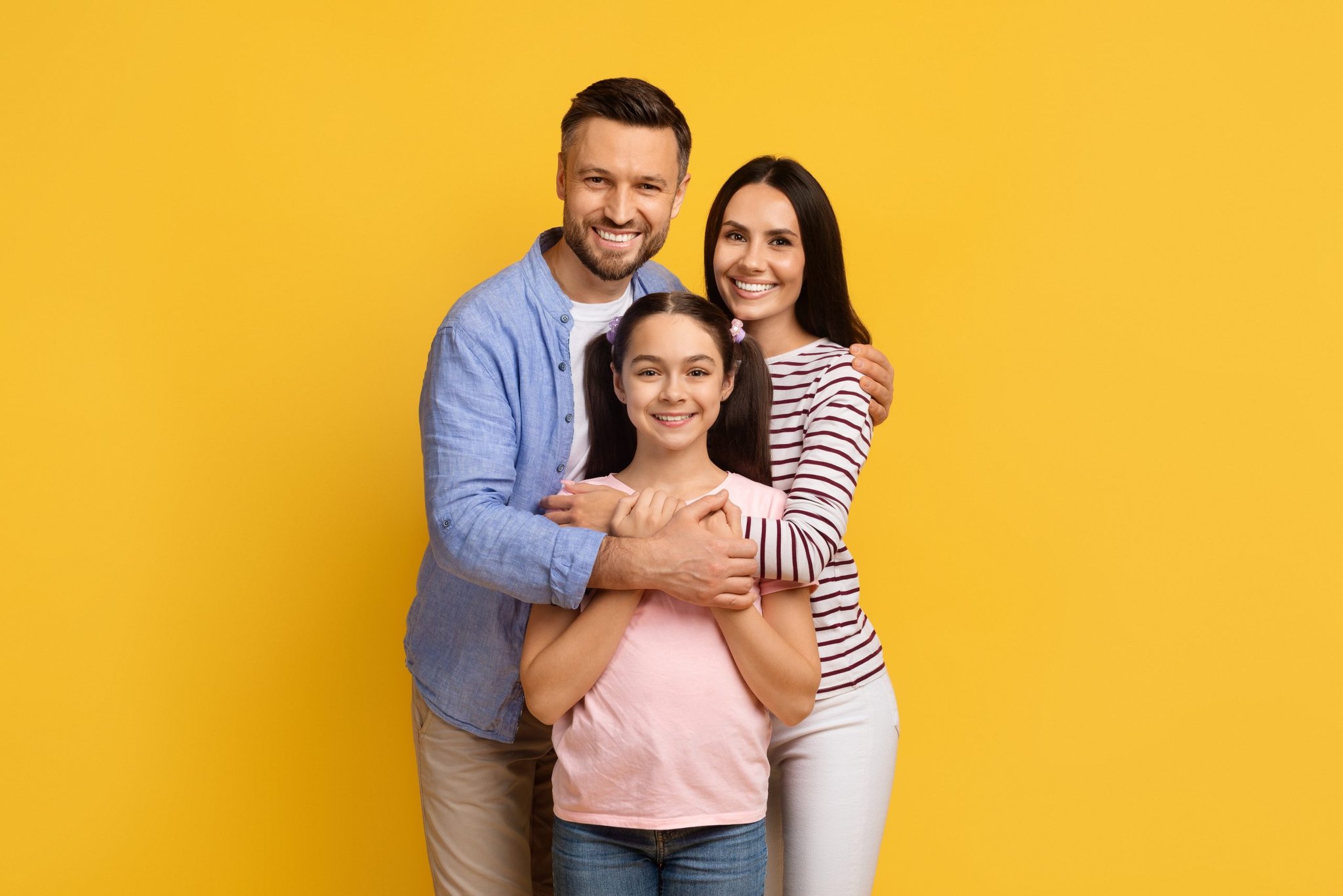 Parents embrace their daughter as all three smile