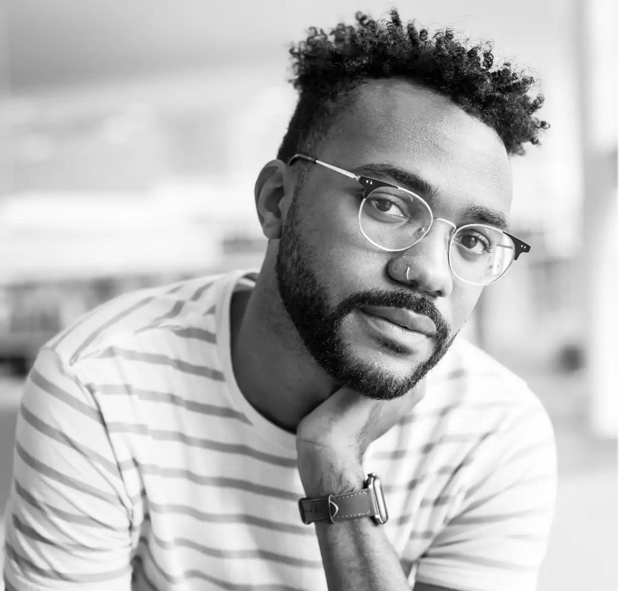 Man wearing glasses rests his chin on his hand