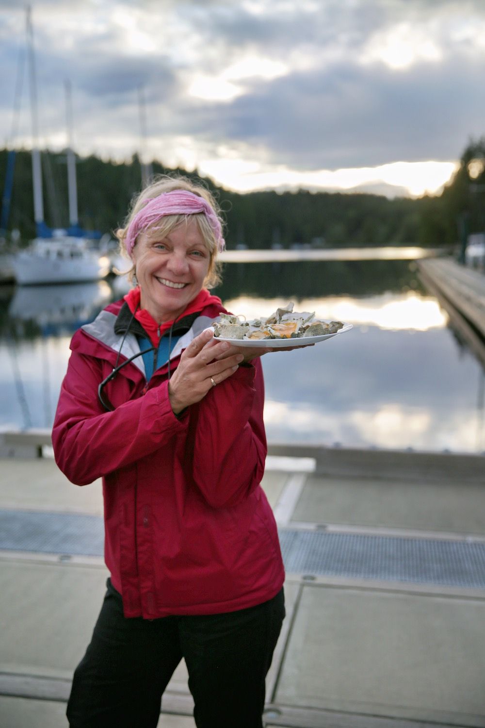Woman holds a plate of oysters at a marina