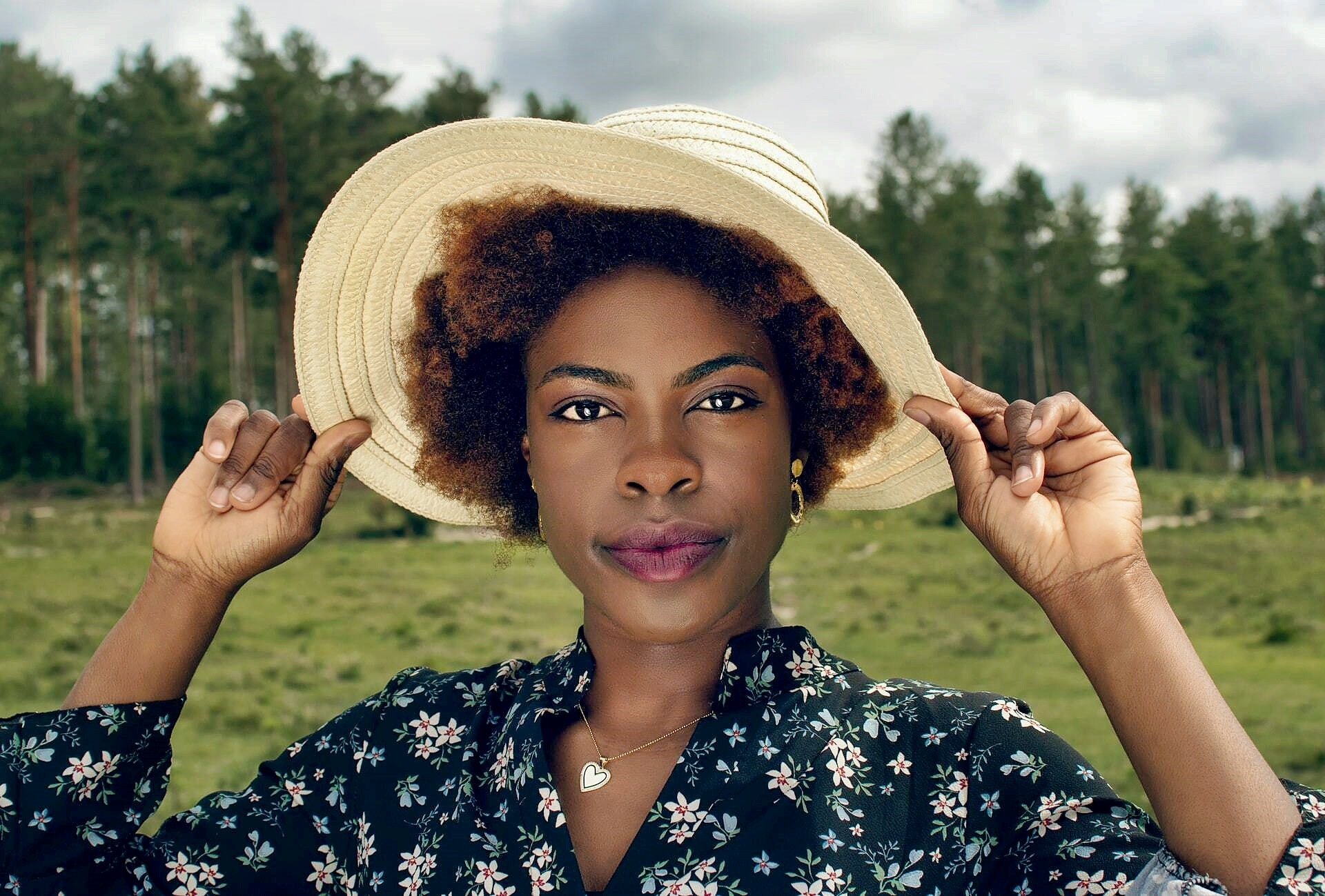 Woman holding the brim of her sun hat in a field