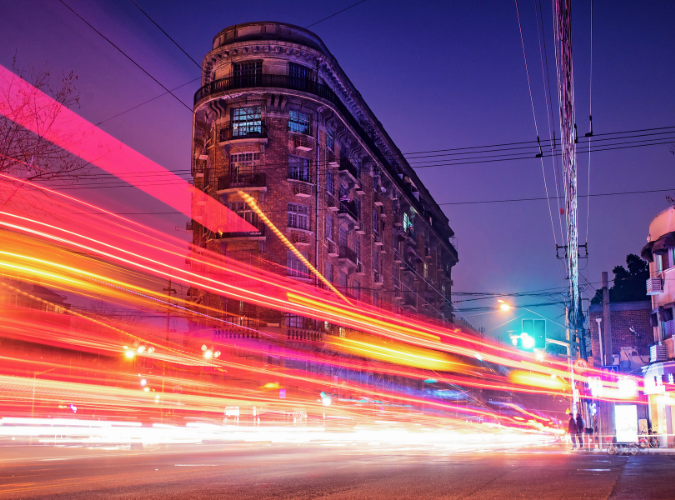 Historic corner building behind traffic light trails at night