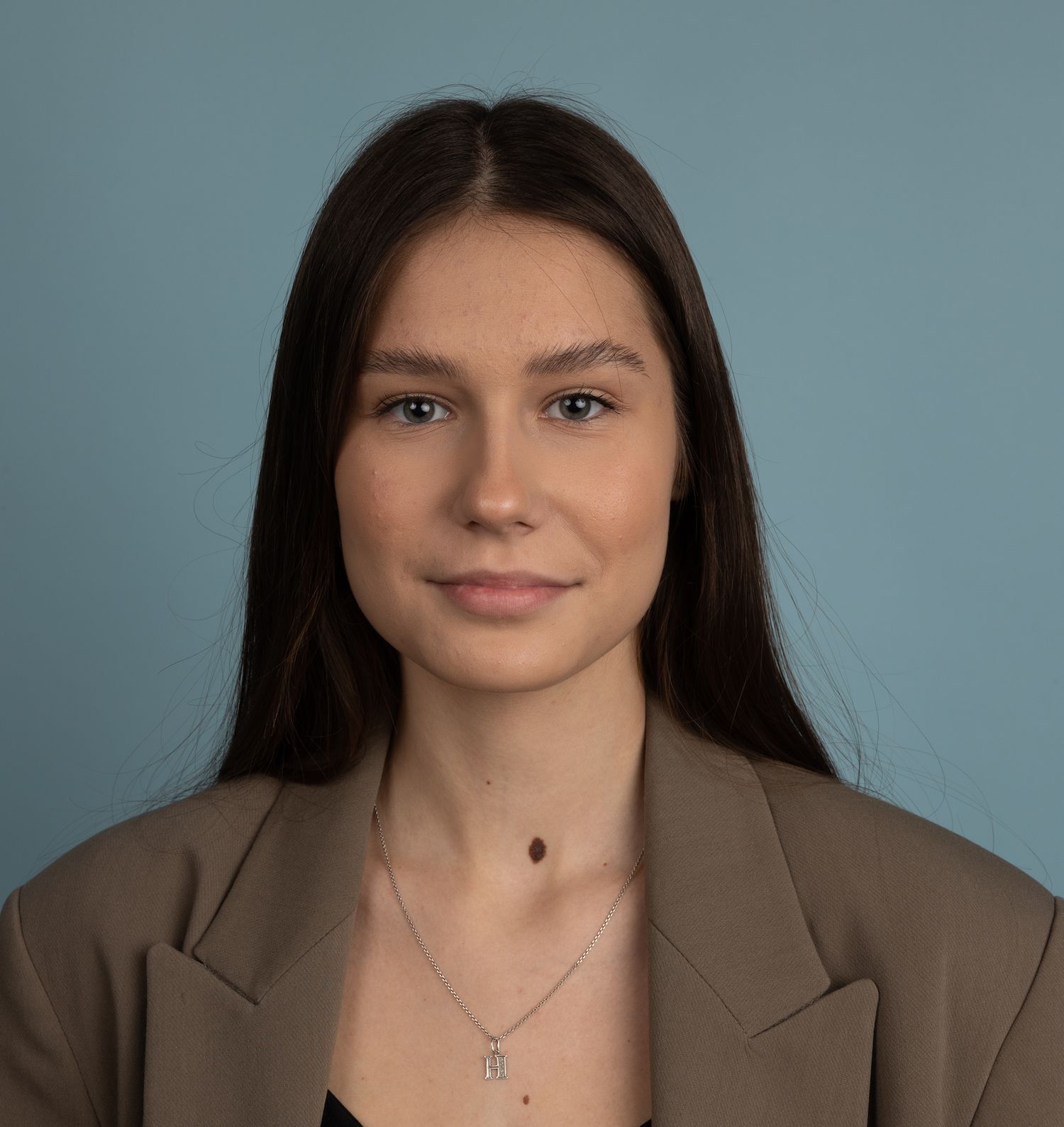 Woman with long dark hair wearing a blazer and necklace