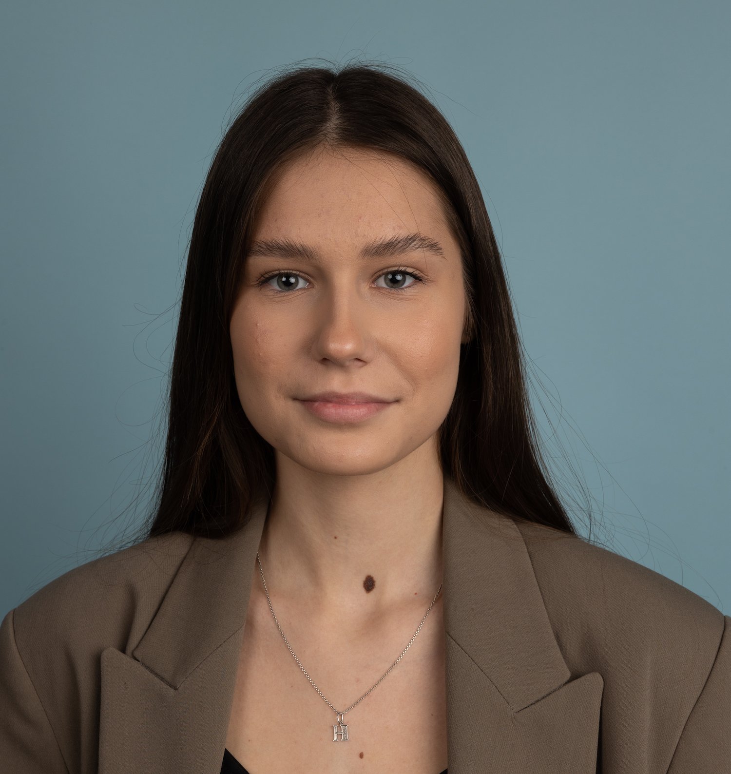 Woman with long dark hair wearing a blazer and necklace