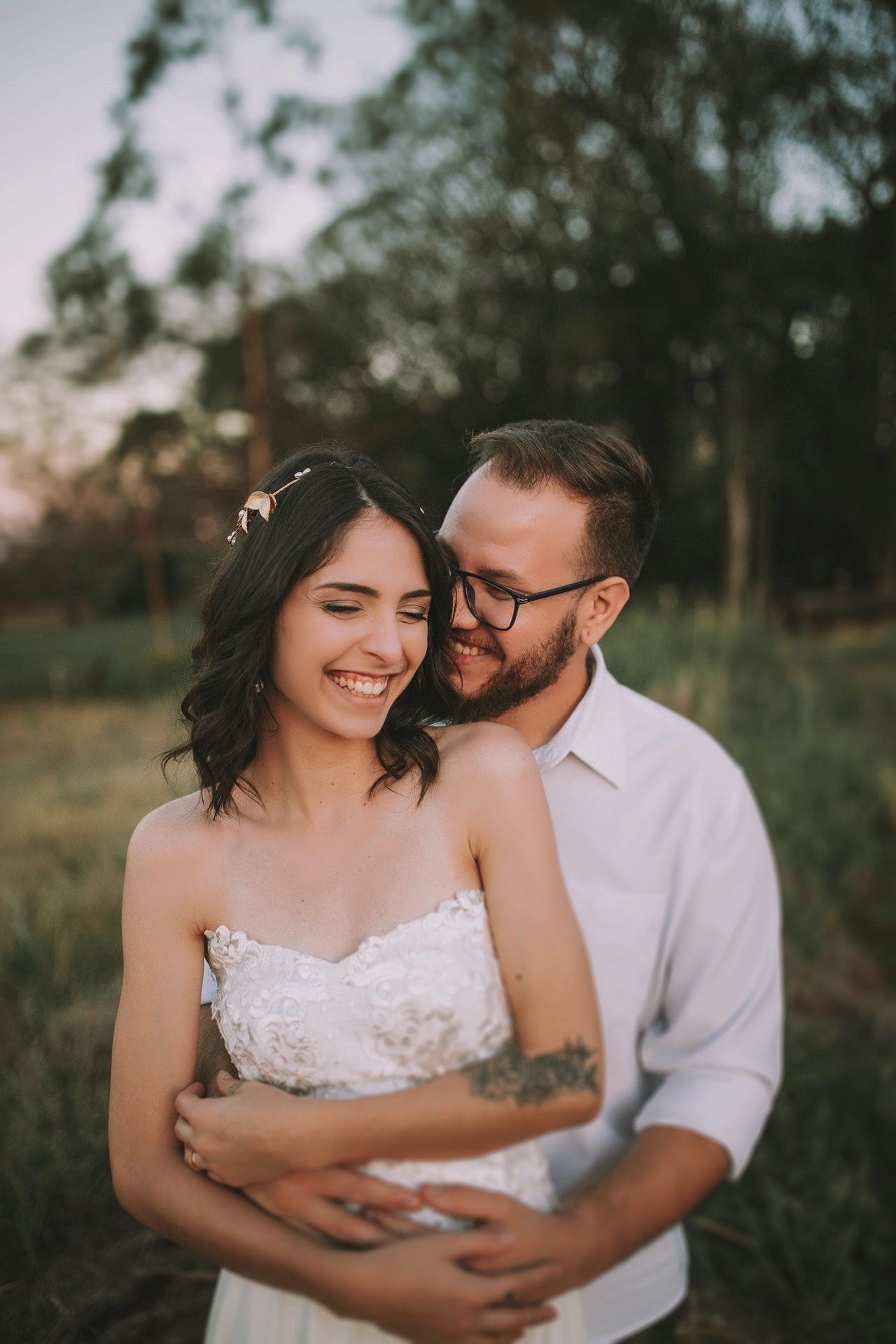 Smiling couple embrace outdoors, with woman wearing a wedding dress