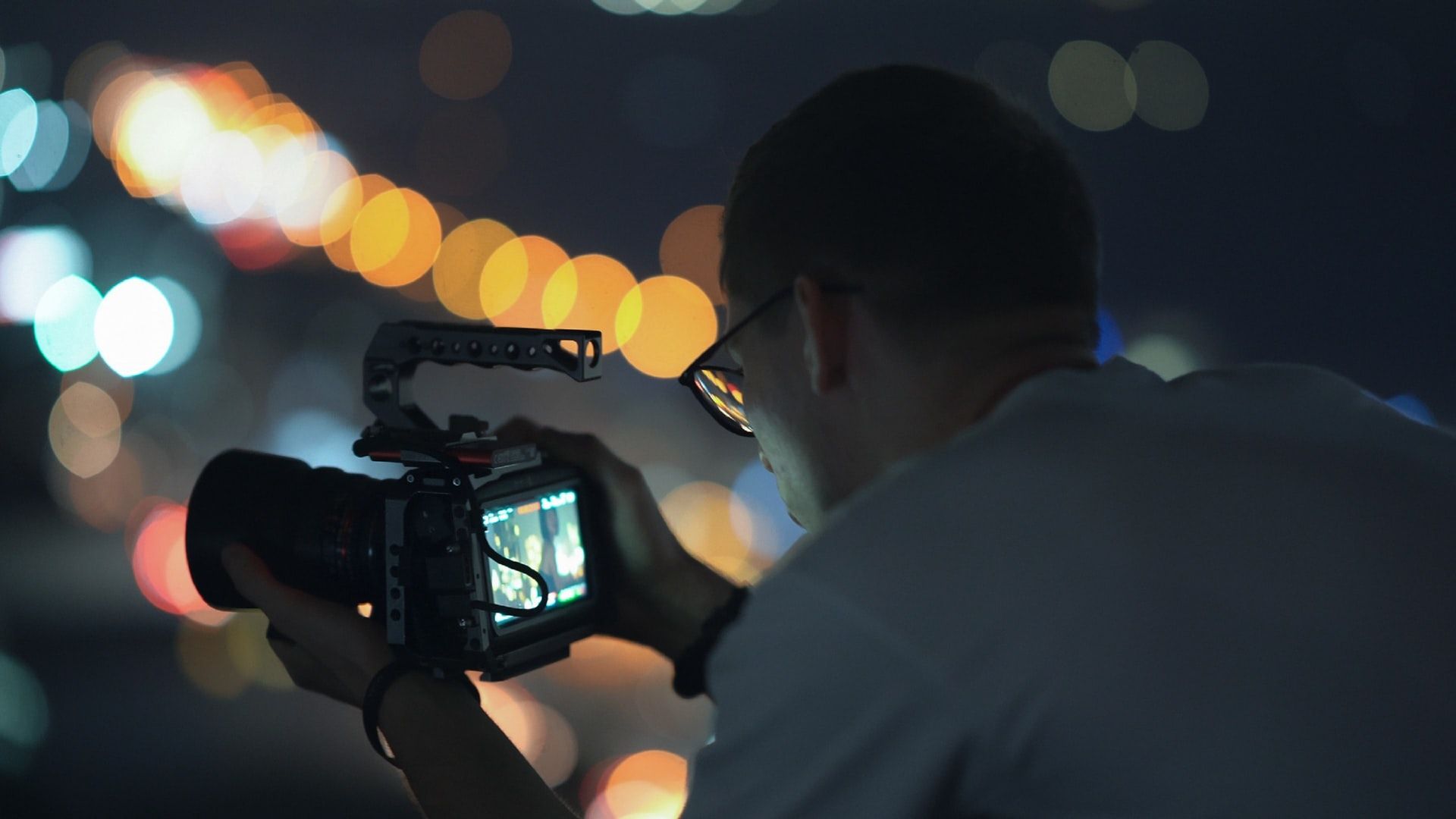 Camera operator filming city lights at night