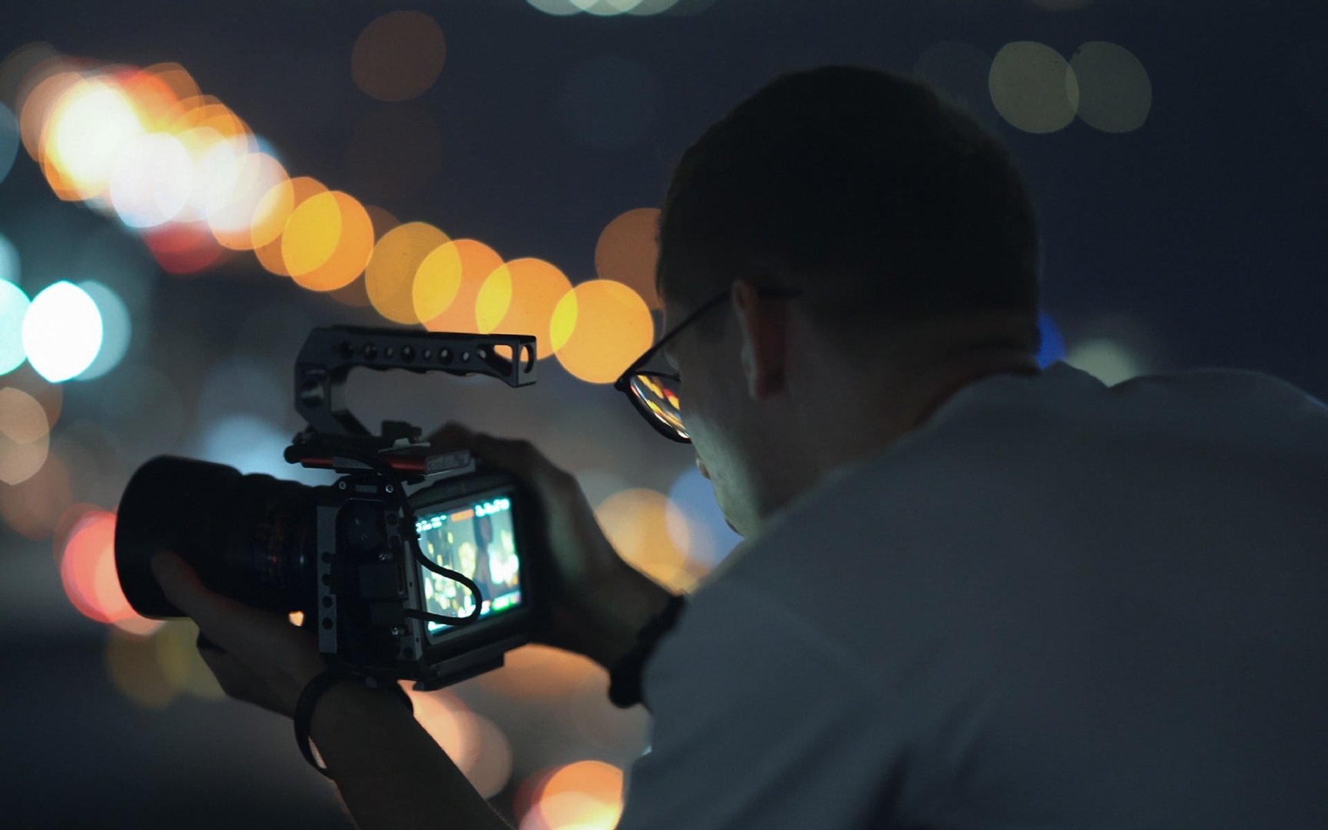 Camera operator filming city lights at night