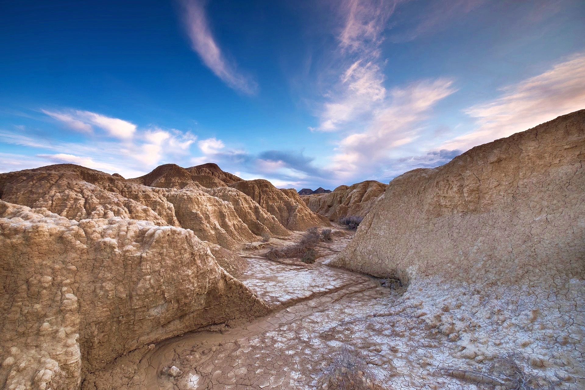 Eroded desert badlands beneath a cloud-streaked sky