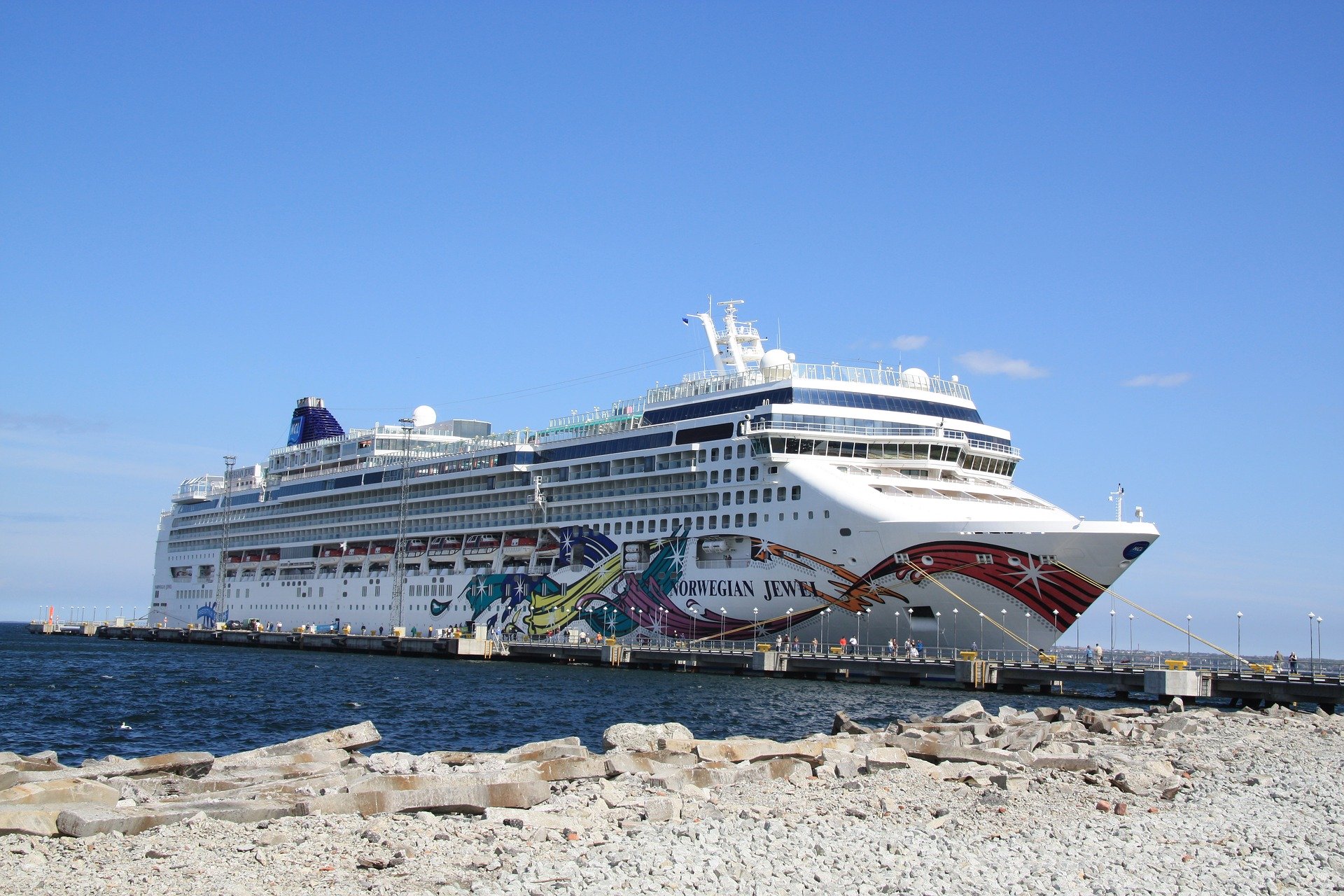 Norwegian Jewel cruise ship docked beside a rocky shoreline
