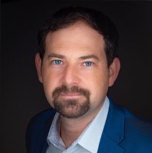 Man with dark hair and goatee wearing a suit jacket