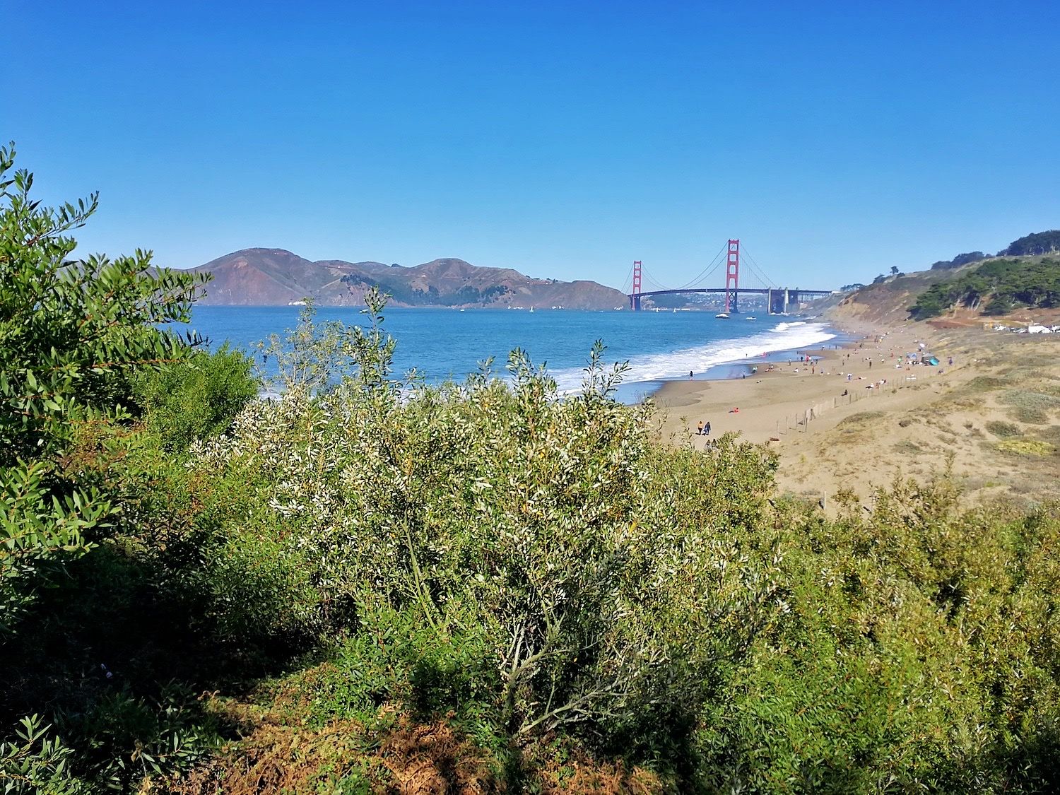 Golden Gate Bridge spans the bay beyond a populated beach
