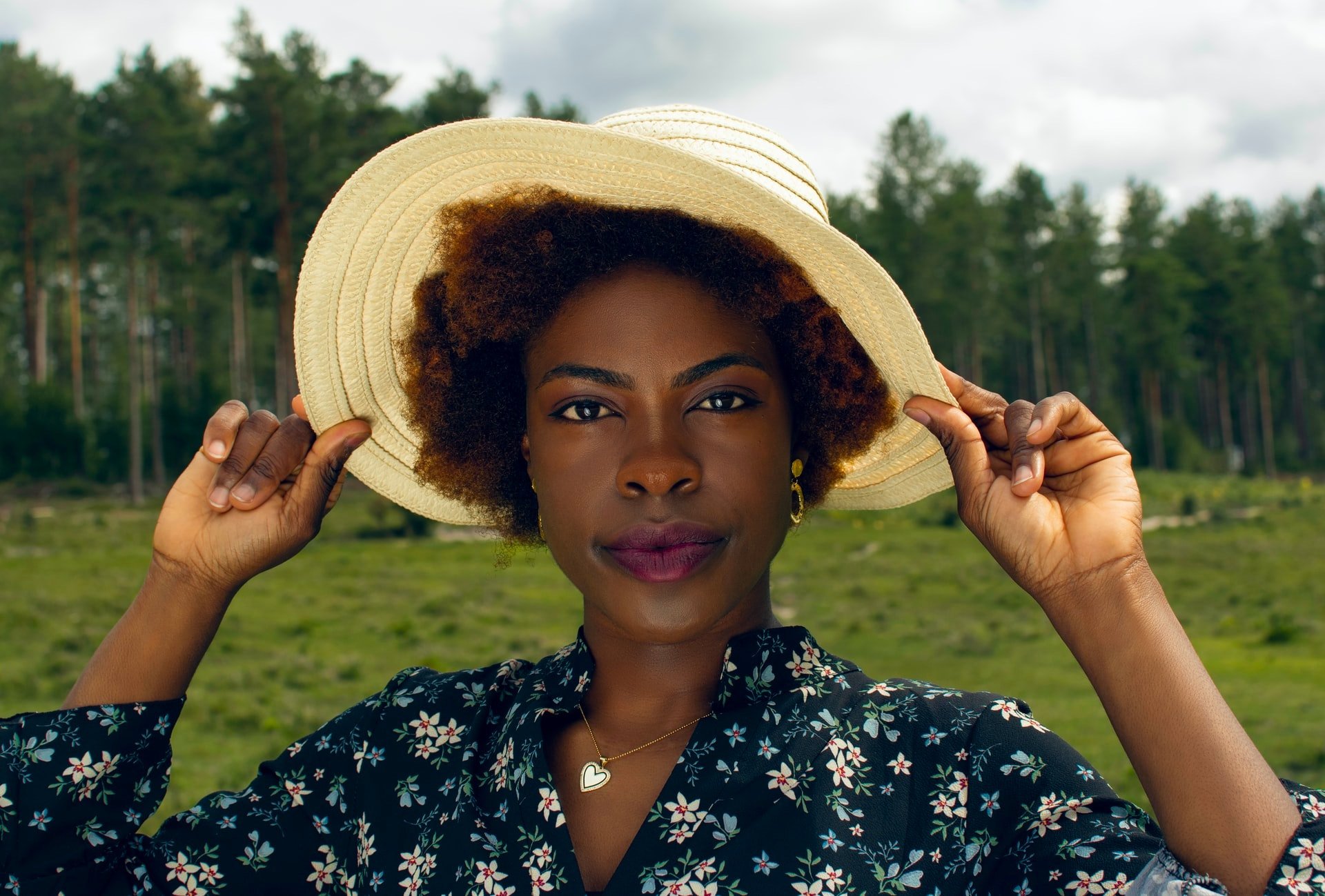 Woman holding the brim of her sun hat in a field