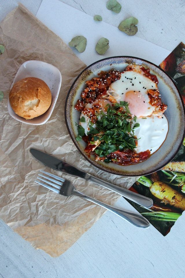 Fried eggs in tomato sauce topped with herbs, served with bread