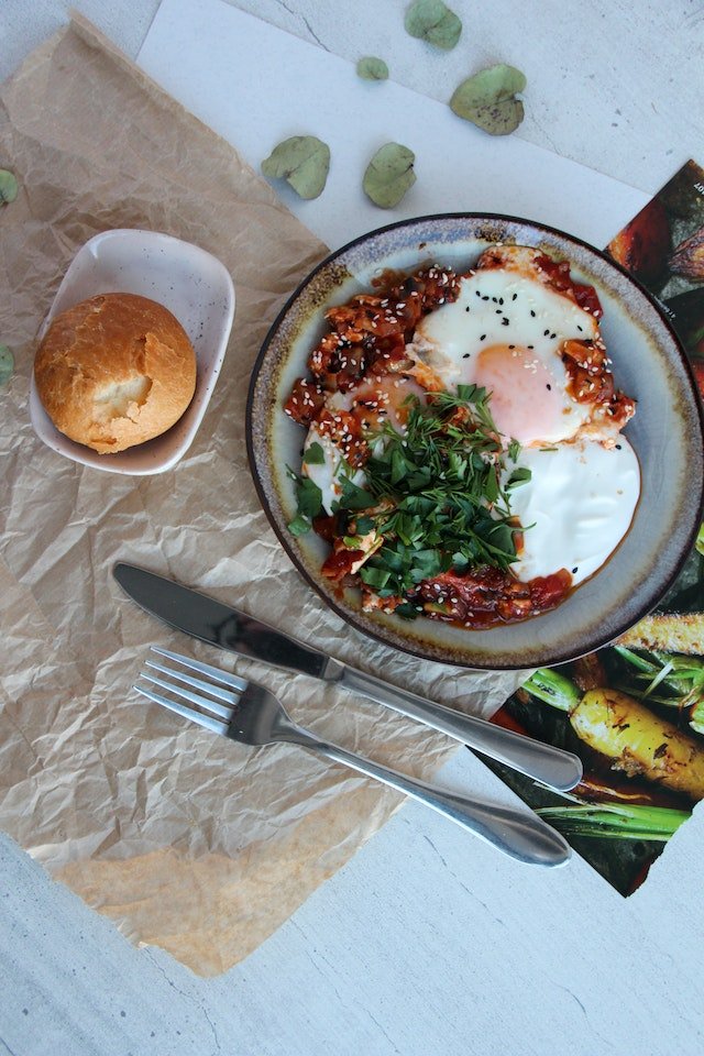 Fried eggs in tomato sauce topped with herbs, served with bread