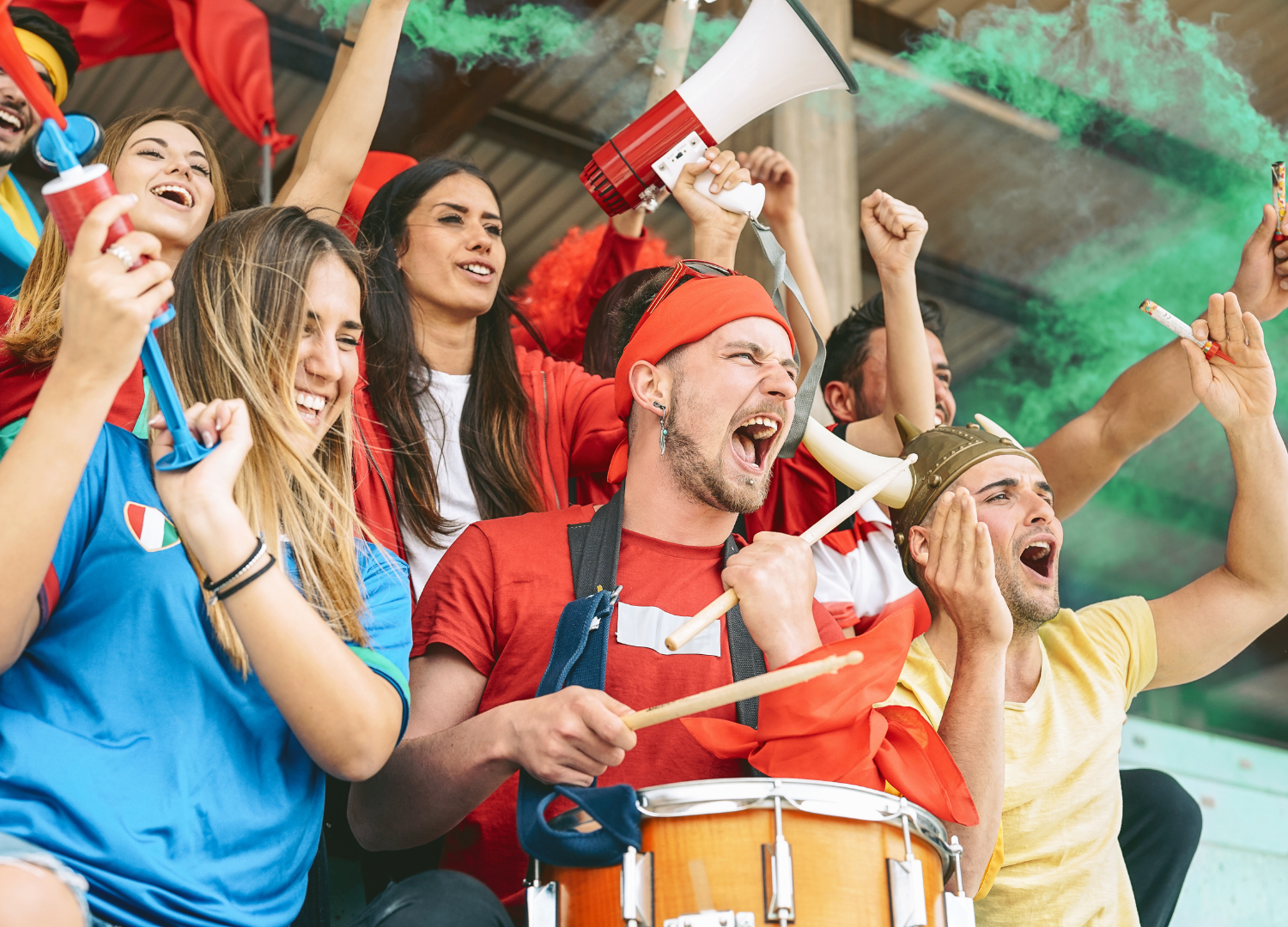 Football fans cheering with a drum and megaphone in the stands
