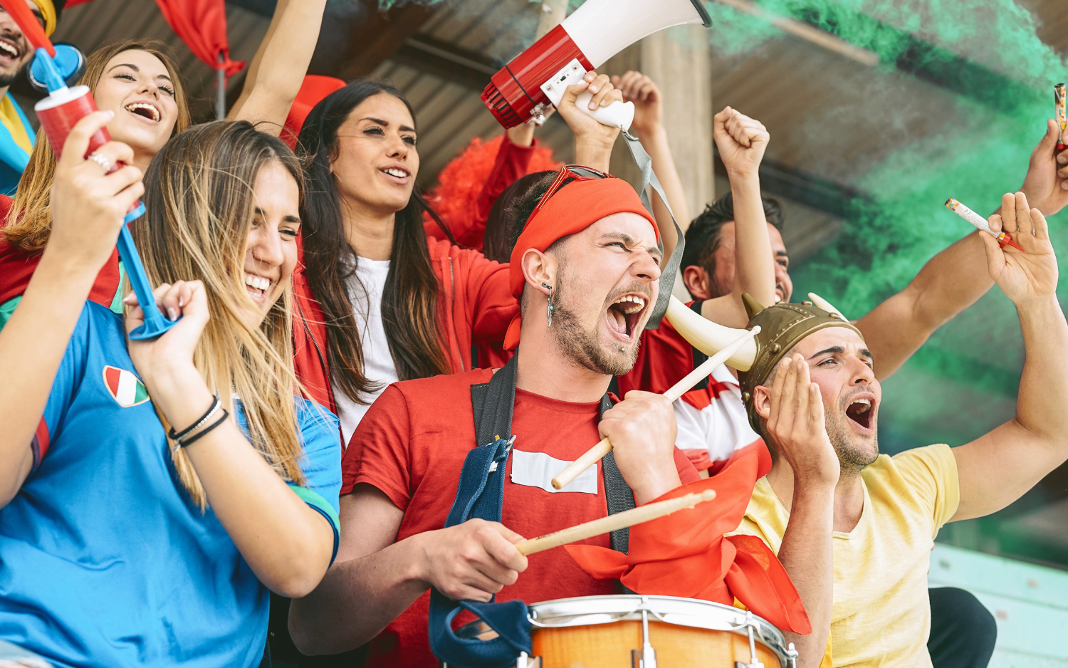 Football fans cheering with a drum and megaphone in the stands