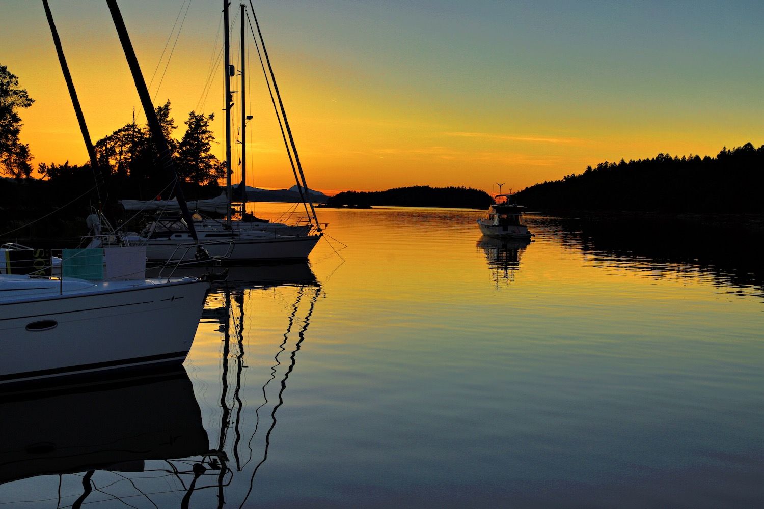 Sailboats moored in a calm harbour at sunset after automatic correction