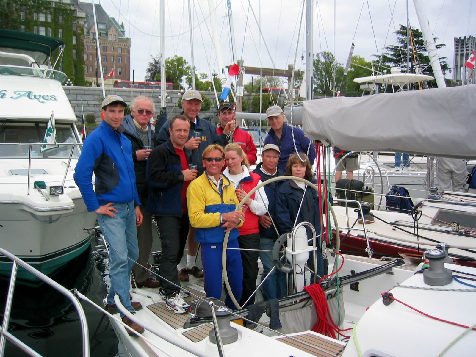 Sailing crew posing together on a yacht in a marina after correction
