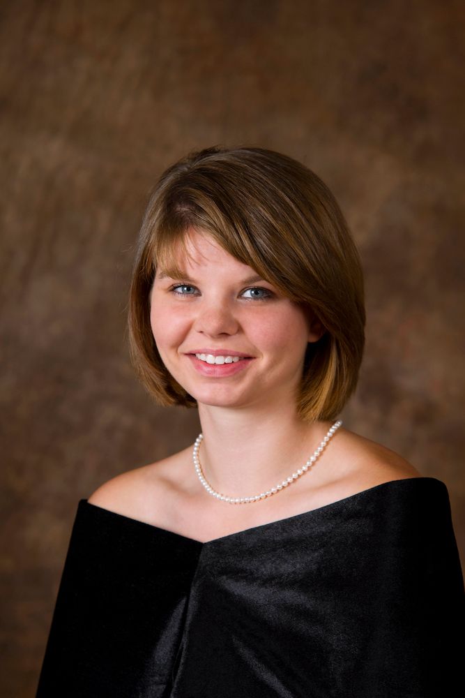 Portrait of a smiling young woman with a bob haircut and a pearl necklace