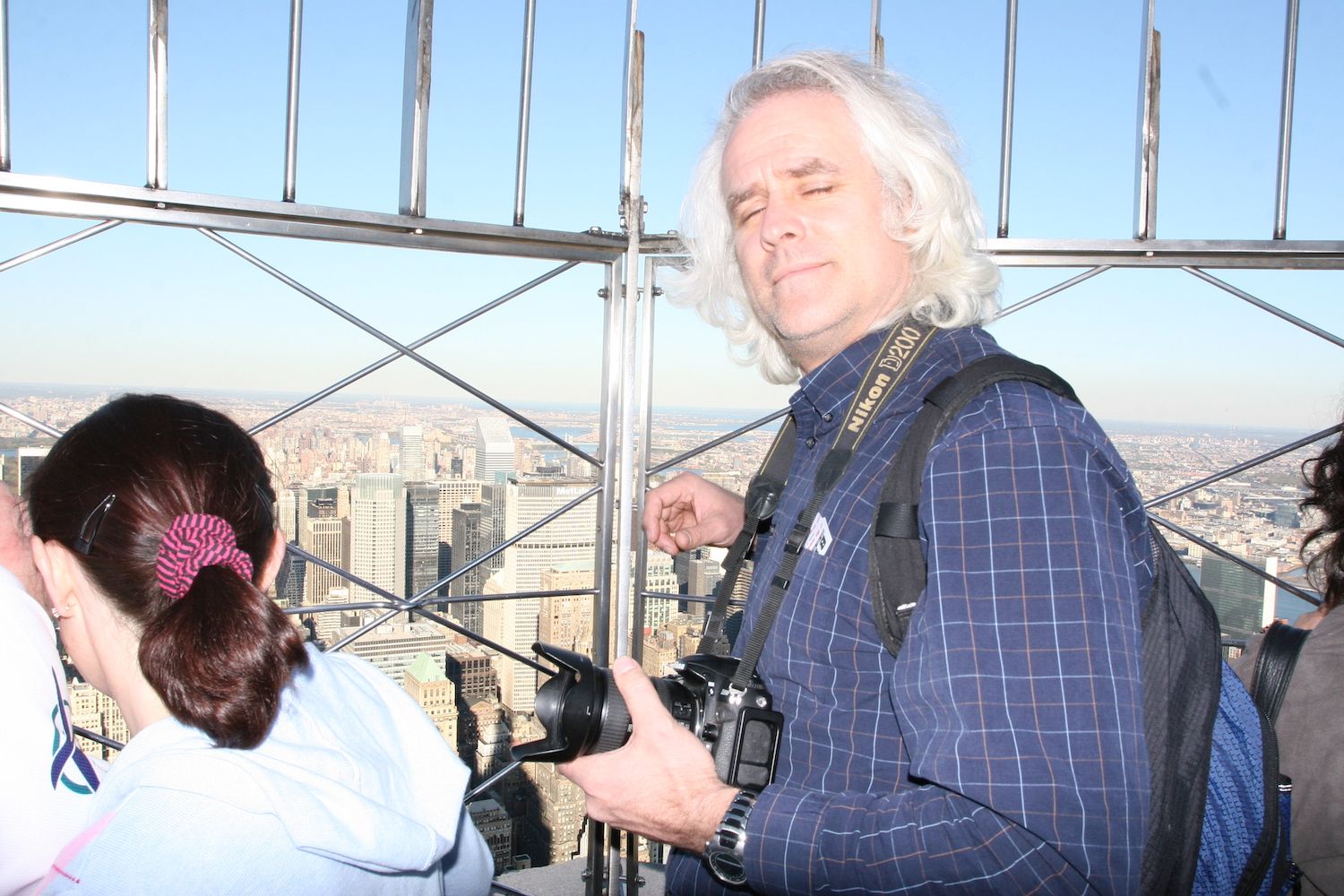 Man with a Nikon camera at a skyscraper observation deck overlooking a city