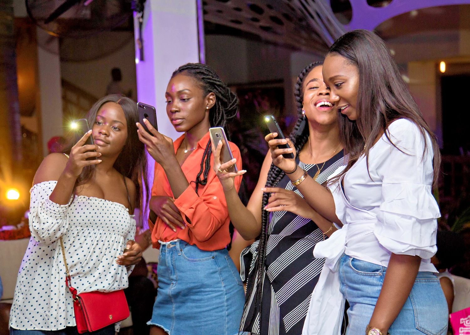 Four women looking at their phones at an evening event