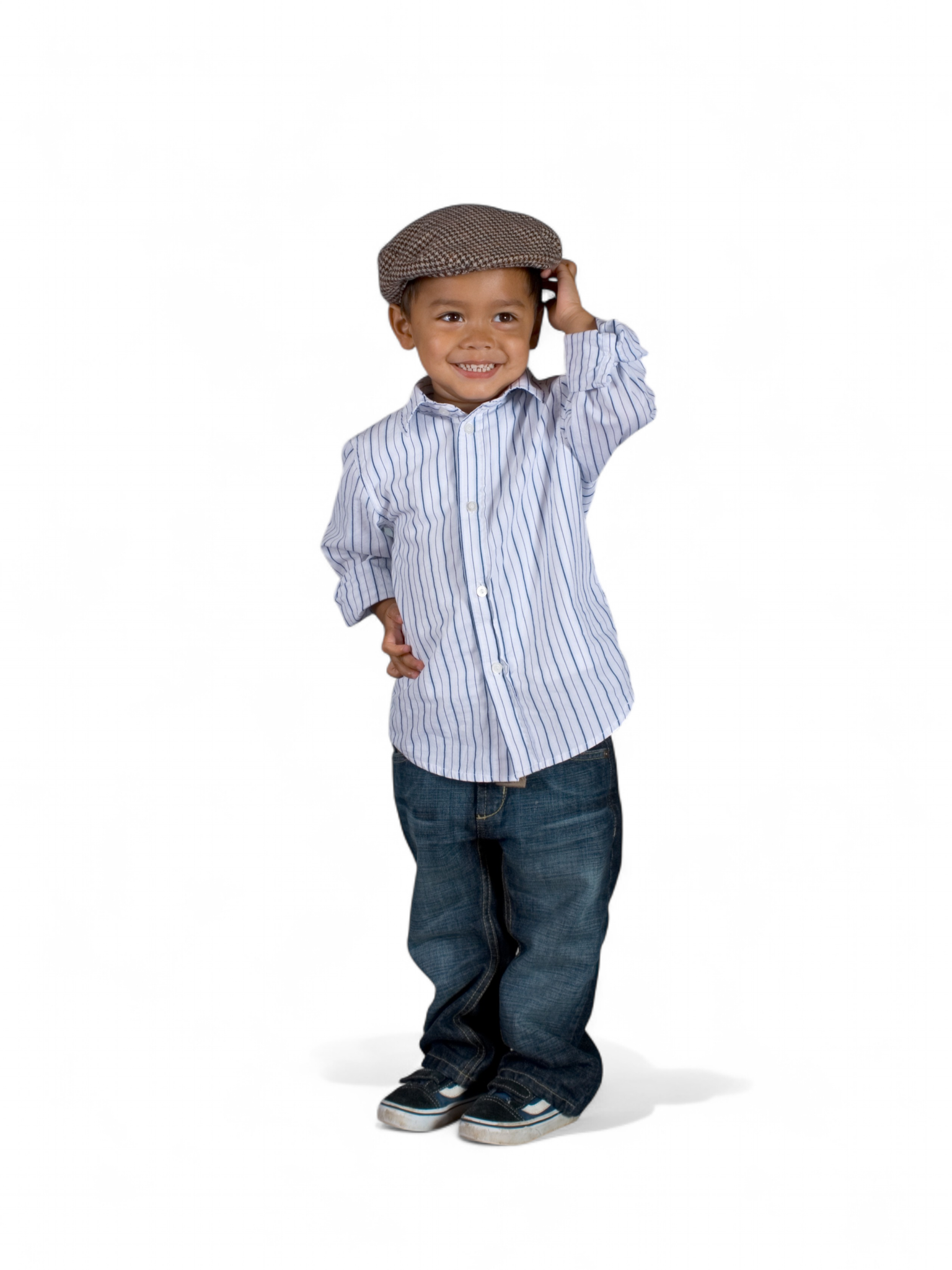 Smiling toddler in a flat cap and striped shirt standing on a plain white background