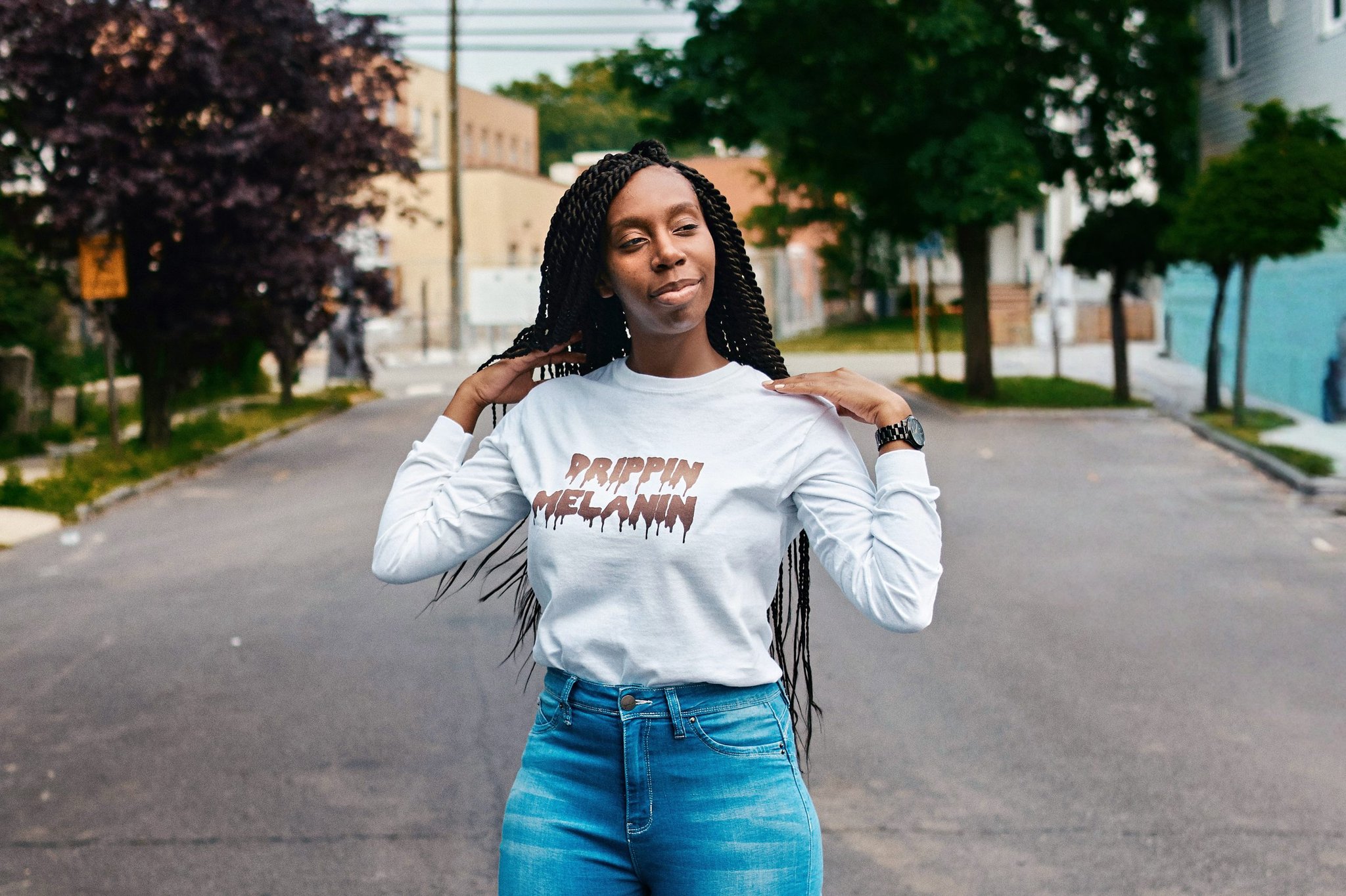 Woman in a "Drippin Melanin" shirt posing on an empty street