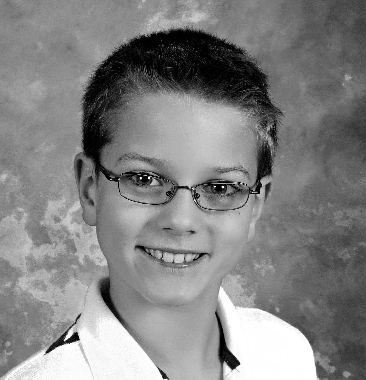 Black and white school portrait of a smiling boy wearing glasses