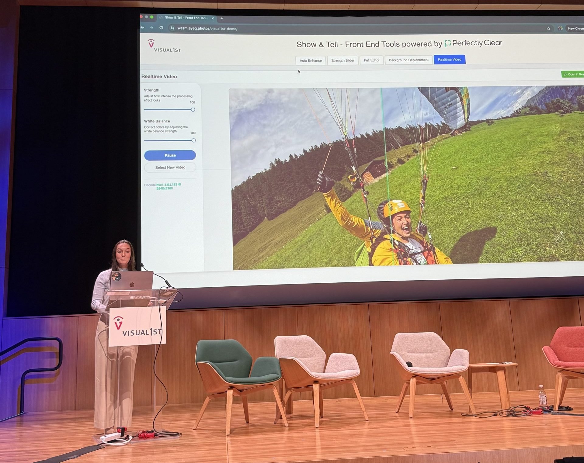 Presenter at a lectern demonstrating "Show & Tell - Front End Tools powered by Perfectly Clear" on stage