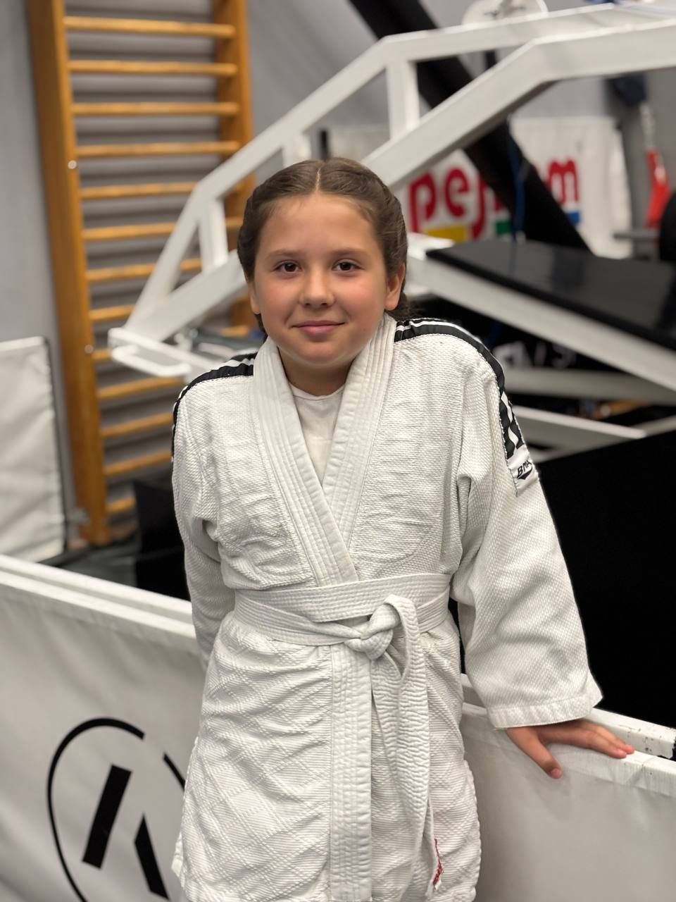 Girl in a white judo gi standing in a training gym
