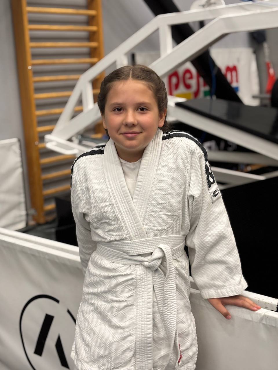 Girl in a white judo gi standing in a training gym