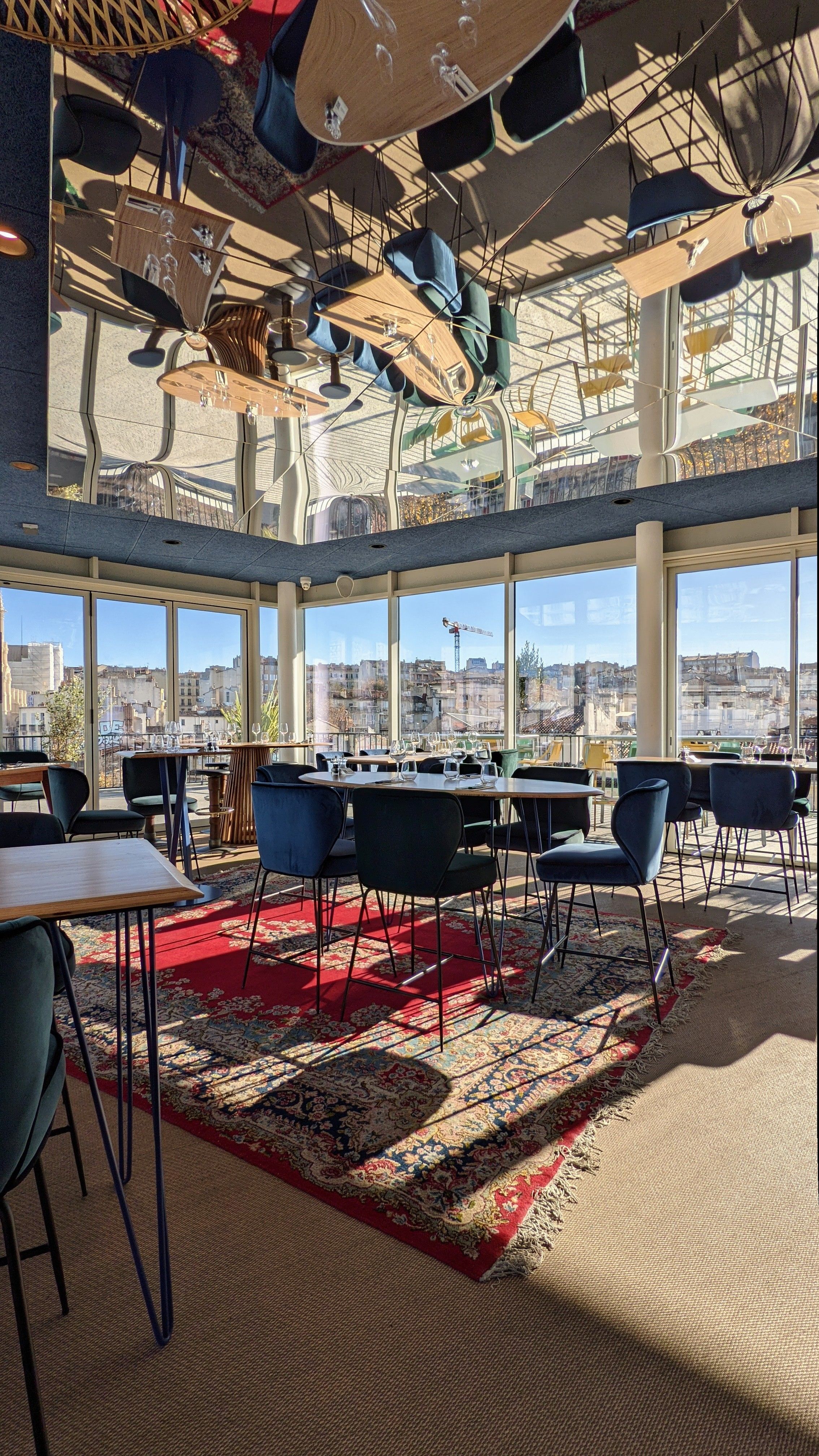 Section image Le bar est ouvert sur une terrasse à 180°, vue imprenable sur les toits marseillais. Le miroir suspendu au plafond reflète l'espace.