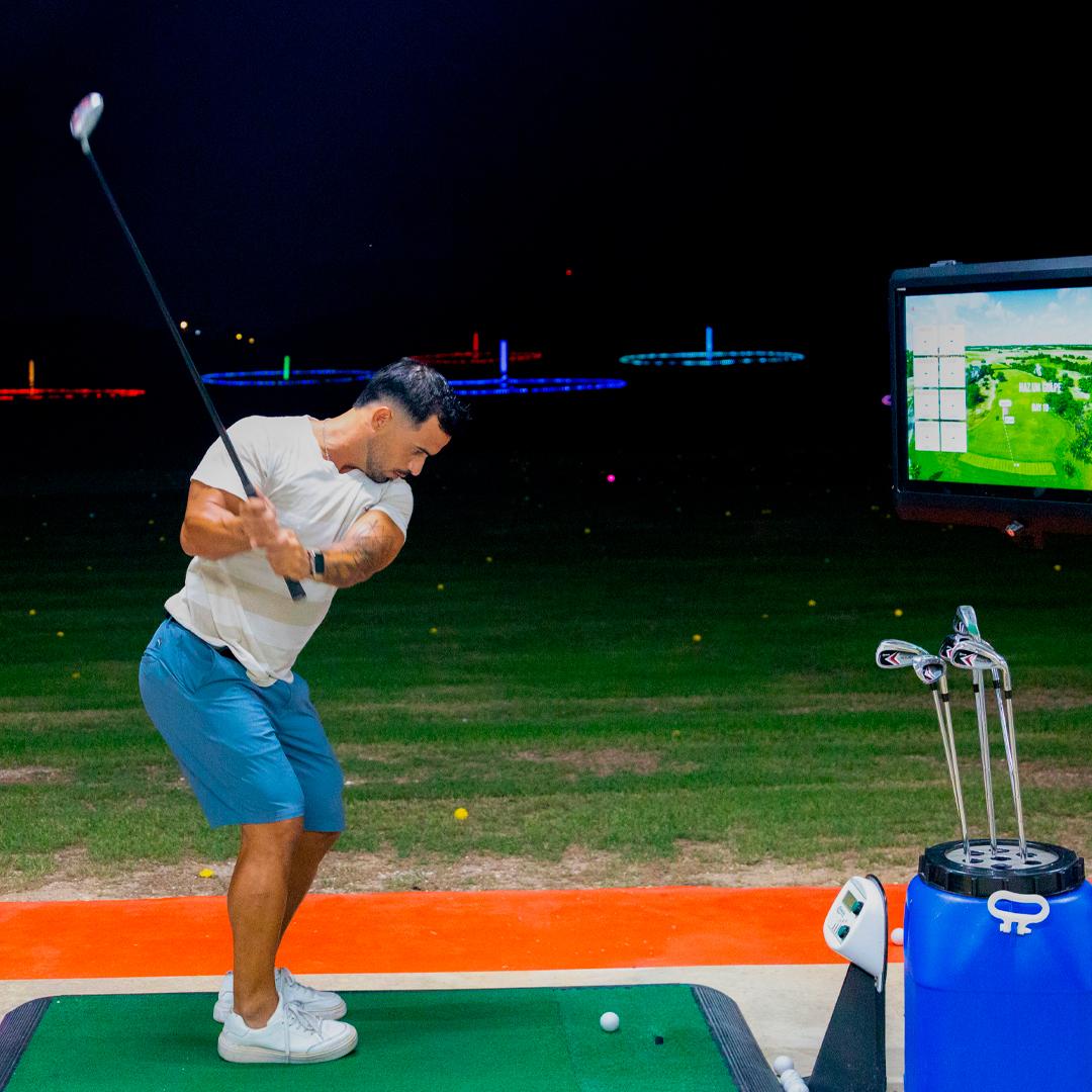 Golfer swinging at Golf N Shots Punta Cana under glow-in-the-dark targets