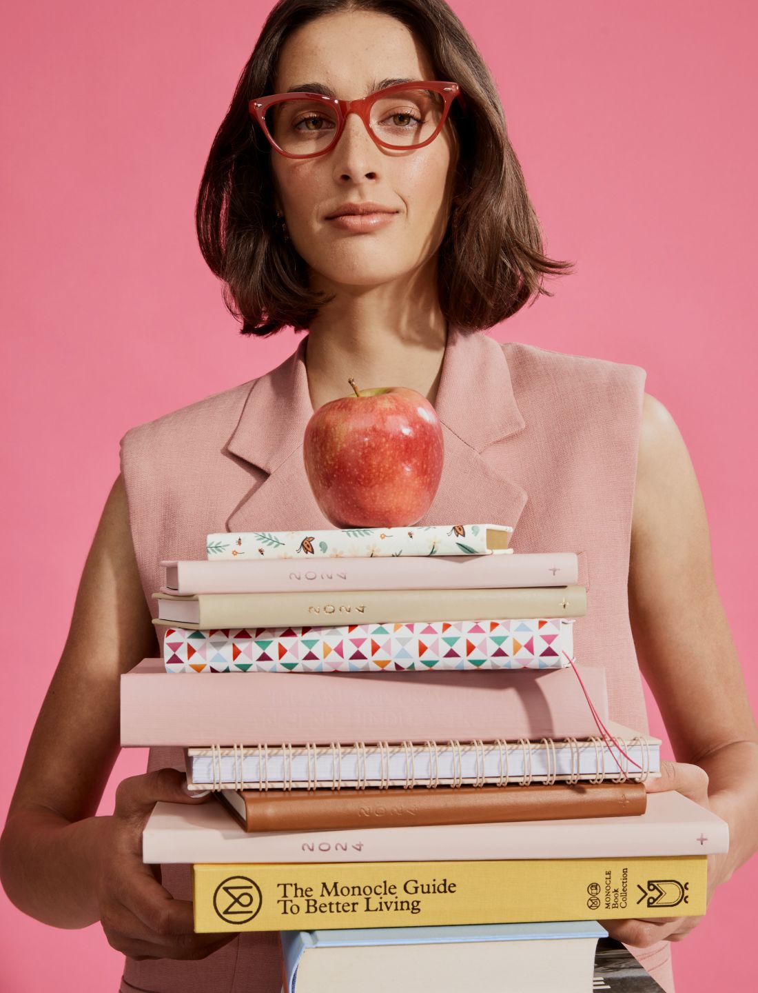 a person holding a stack of books and an apple