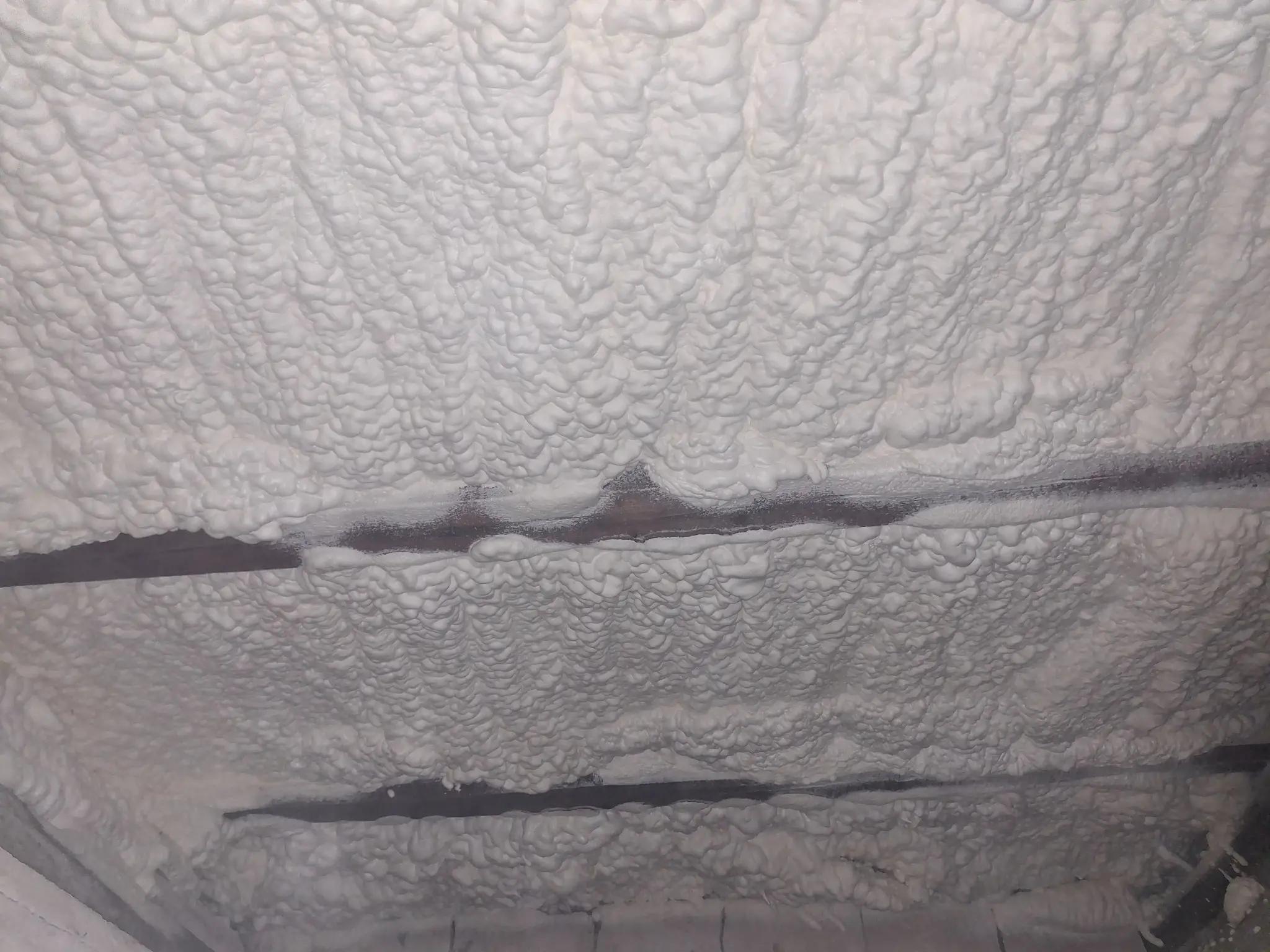 Izolație pod cu spumă poliuretanică cu celulă deschisă aplicată uniform pe grinzi de lemn, lucrare realizată în Drobeta Turnu Severin