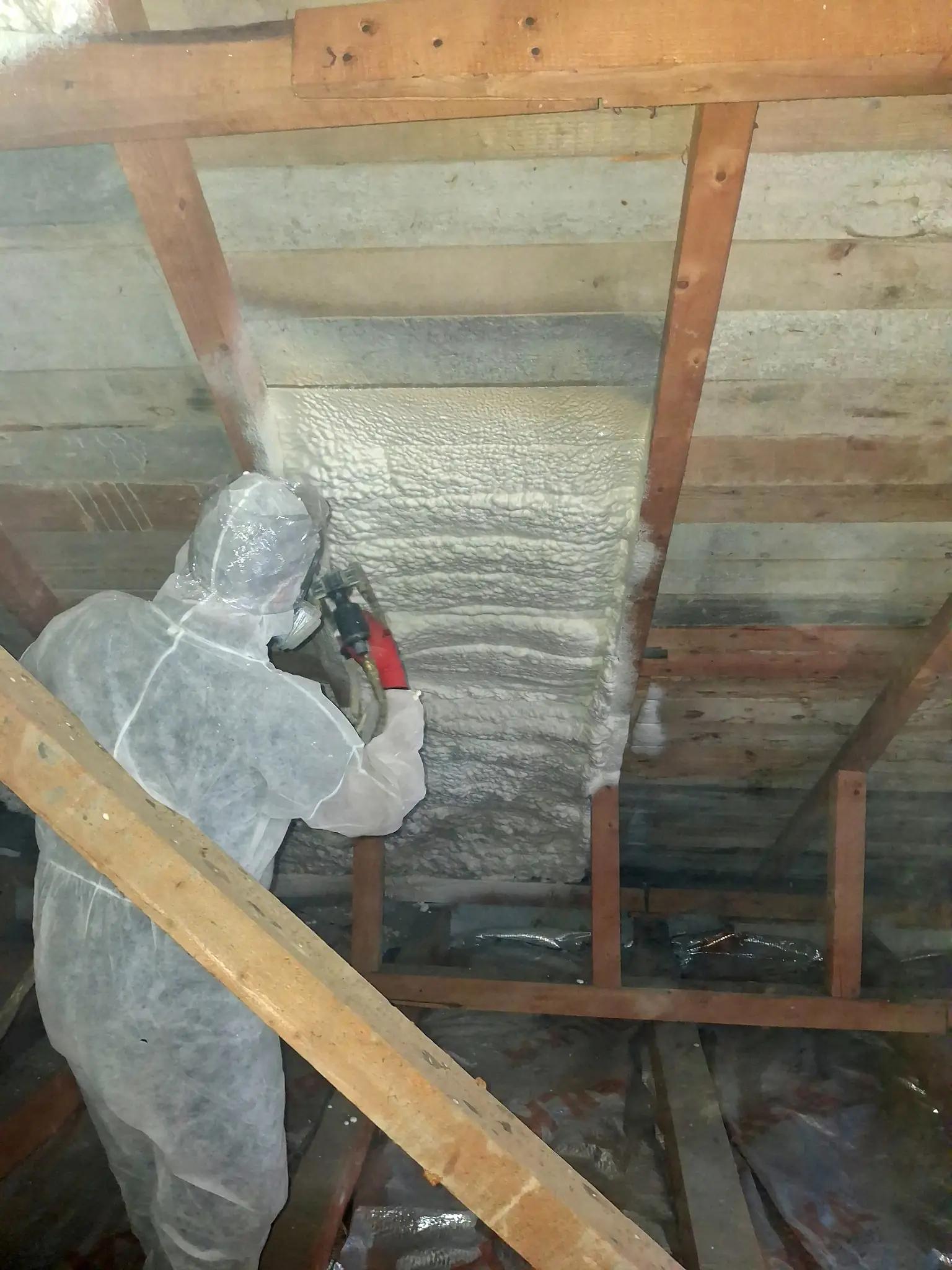 Tehnician aplicând spumă poliuretanică cu celulă deschisă la izolarea mansardei într-o casă din Caineni