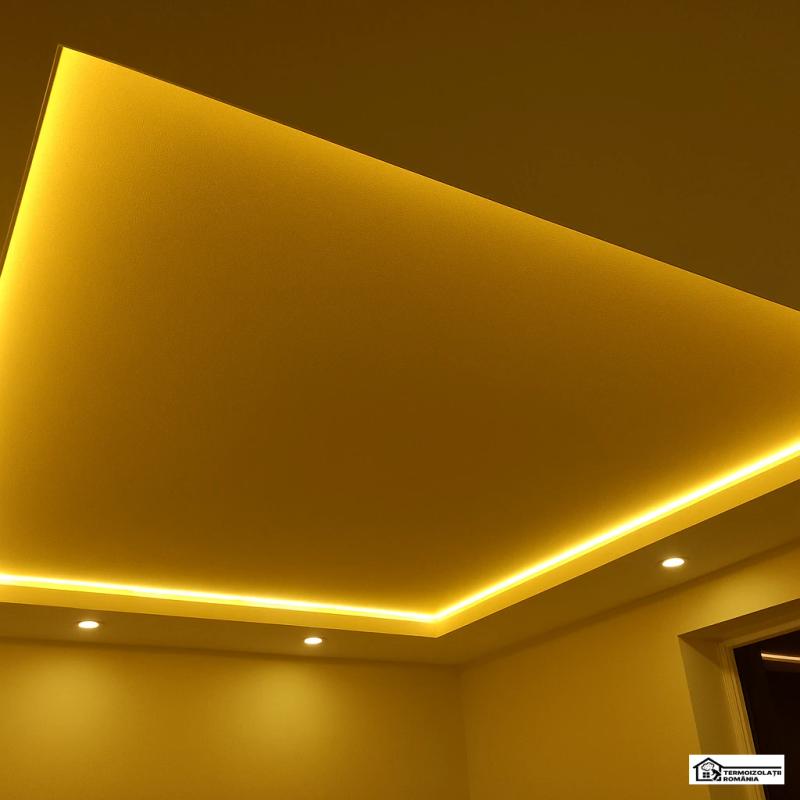 Tavan extensibil satinat auriu cu LED perimetral și candelabru, interior elegant și luxos.