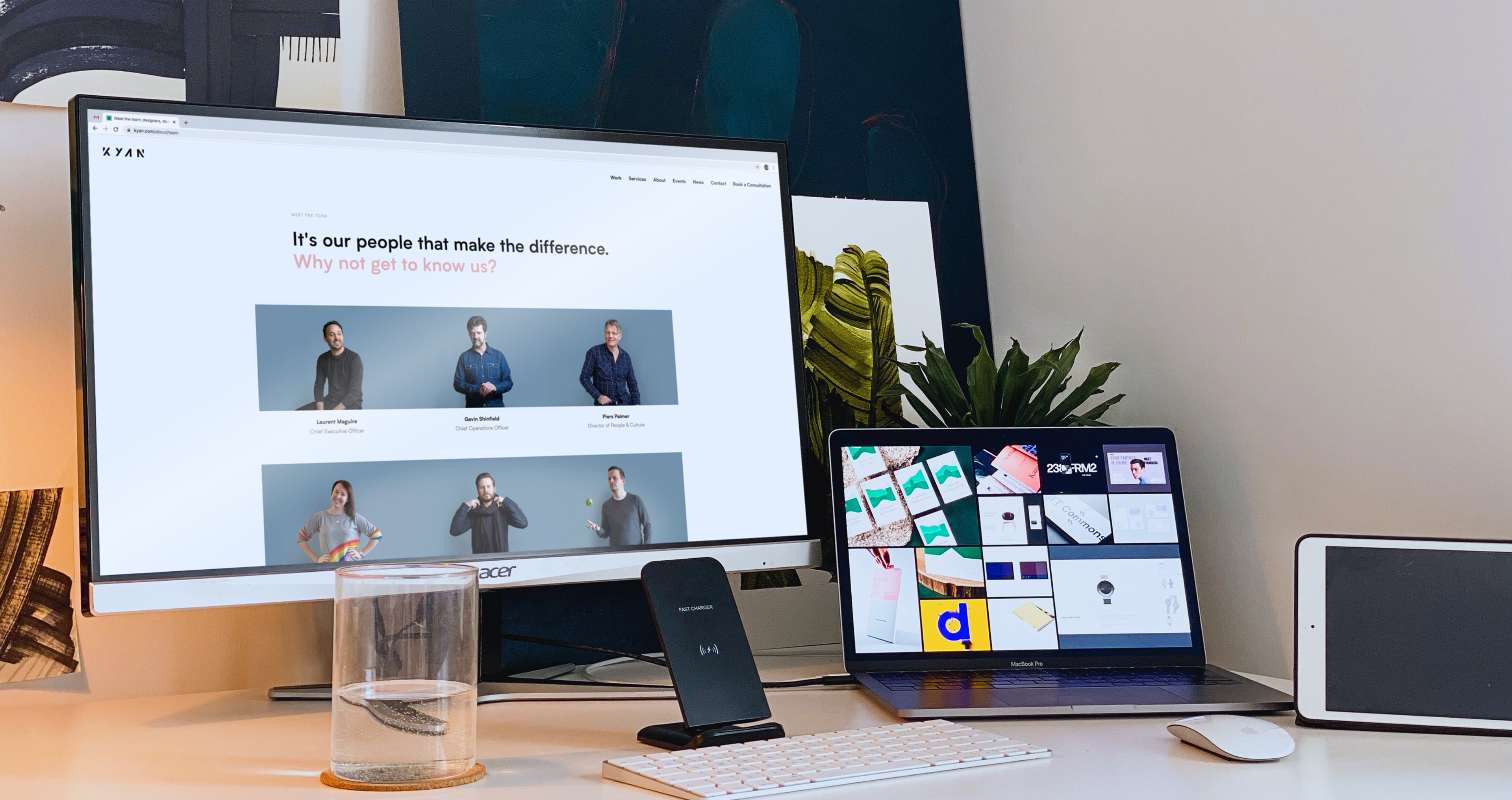 A Kyan employee's home office, featuring multiple screens showing colourful content, surrounded by plants, artwork and desk accessories.