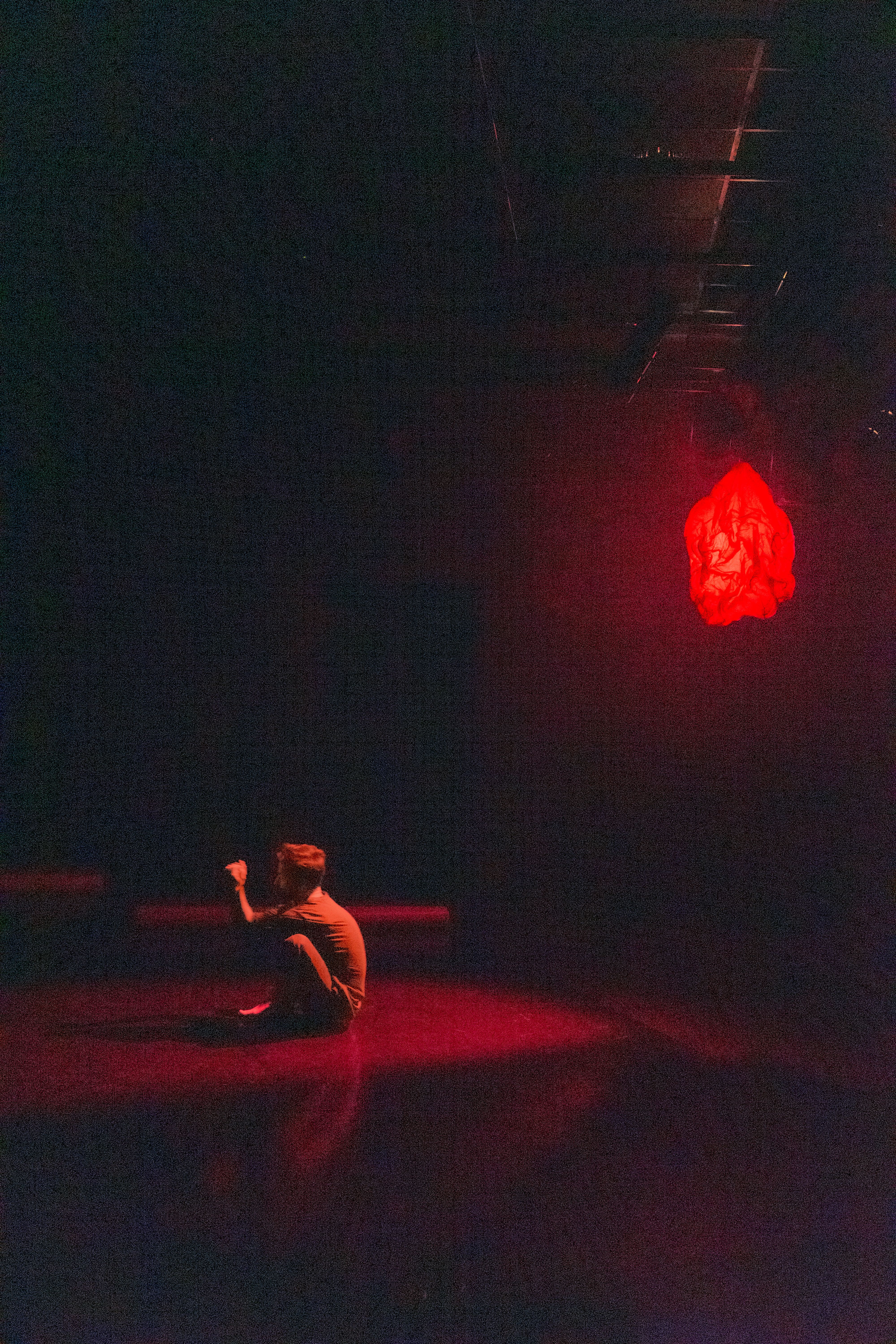 mężczyzna siedzący na scenie w świetle czerwonej lampy