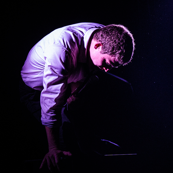 a man touching the platform with his hand in dramatic lighting, saying something into the microphone