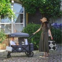 WagonPro City in Titangrau mit Dach beim Einkauf, eine Frau führt ein Kind und Einkaufstüten über Kopfsteinpflaster
