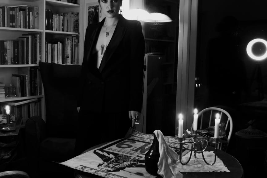 woman in suit standing by table with yiddish poster