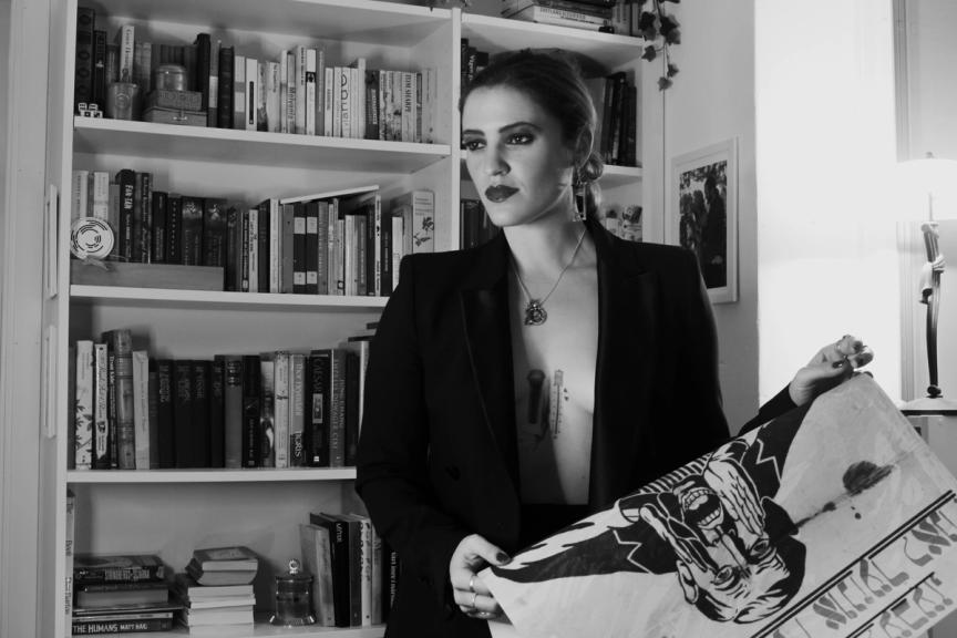 woman in suit holding a yiddish poster