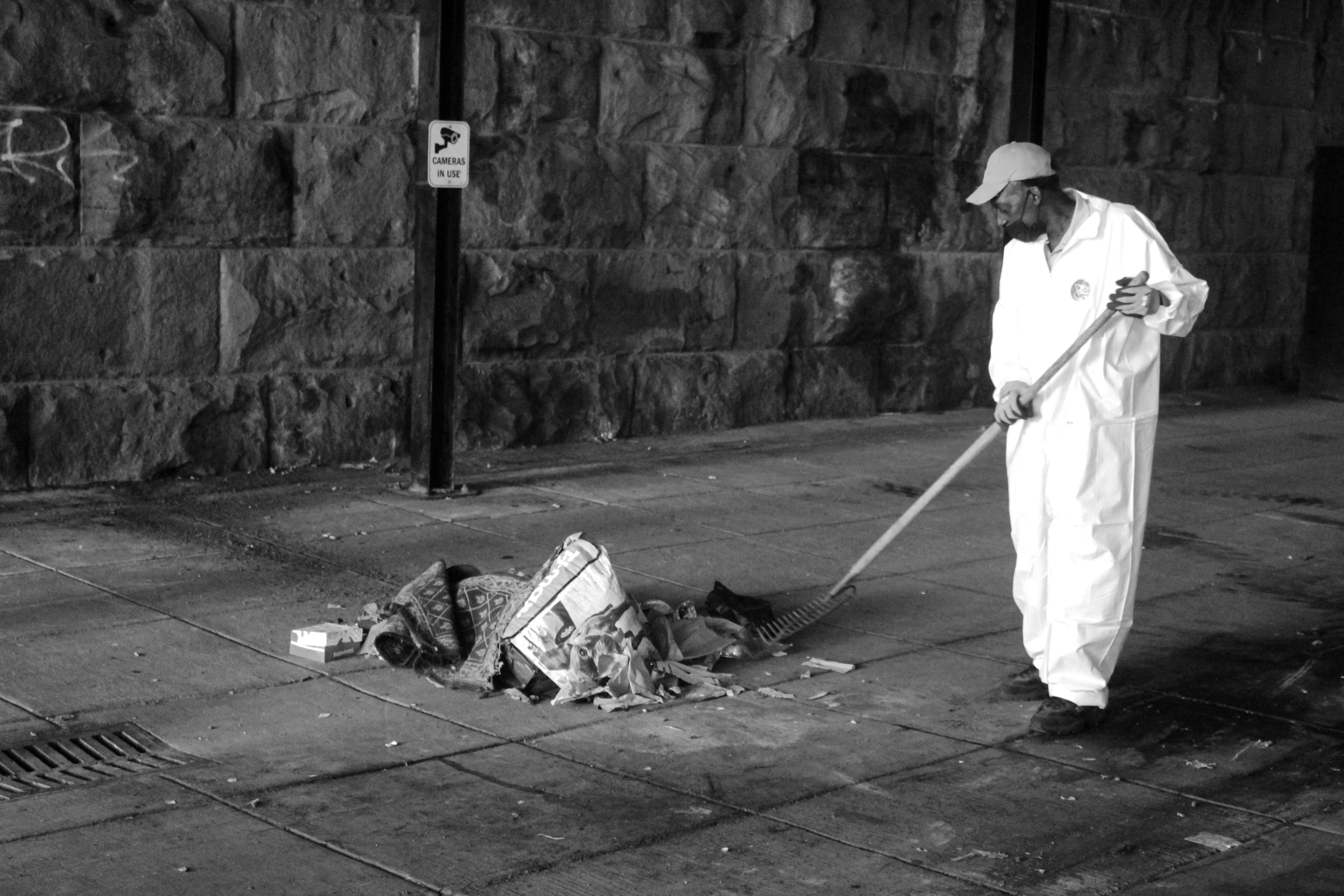 A DC city worker sweeps together a pile of belongings