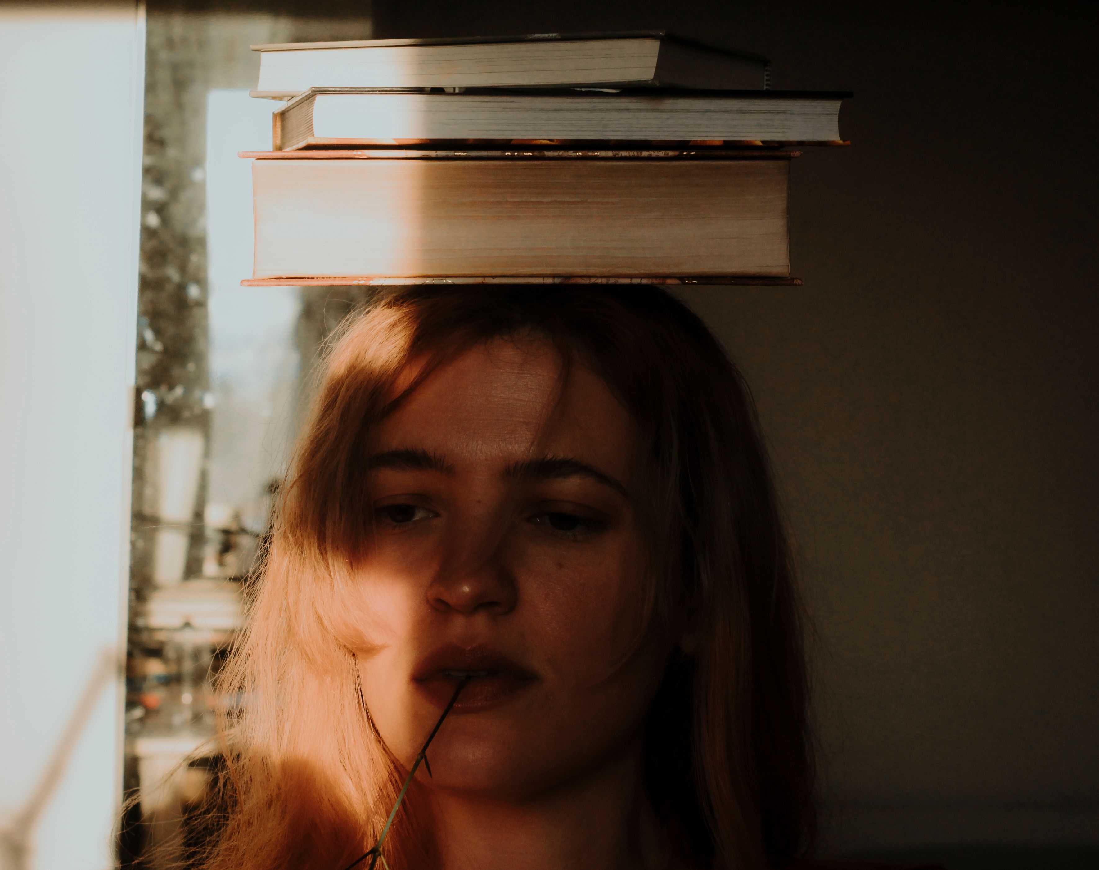 woman with books on her head, reed in mouth