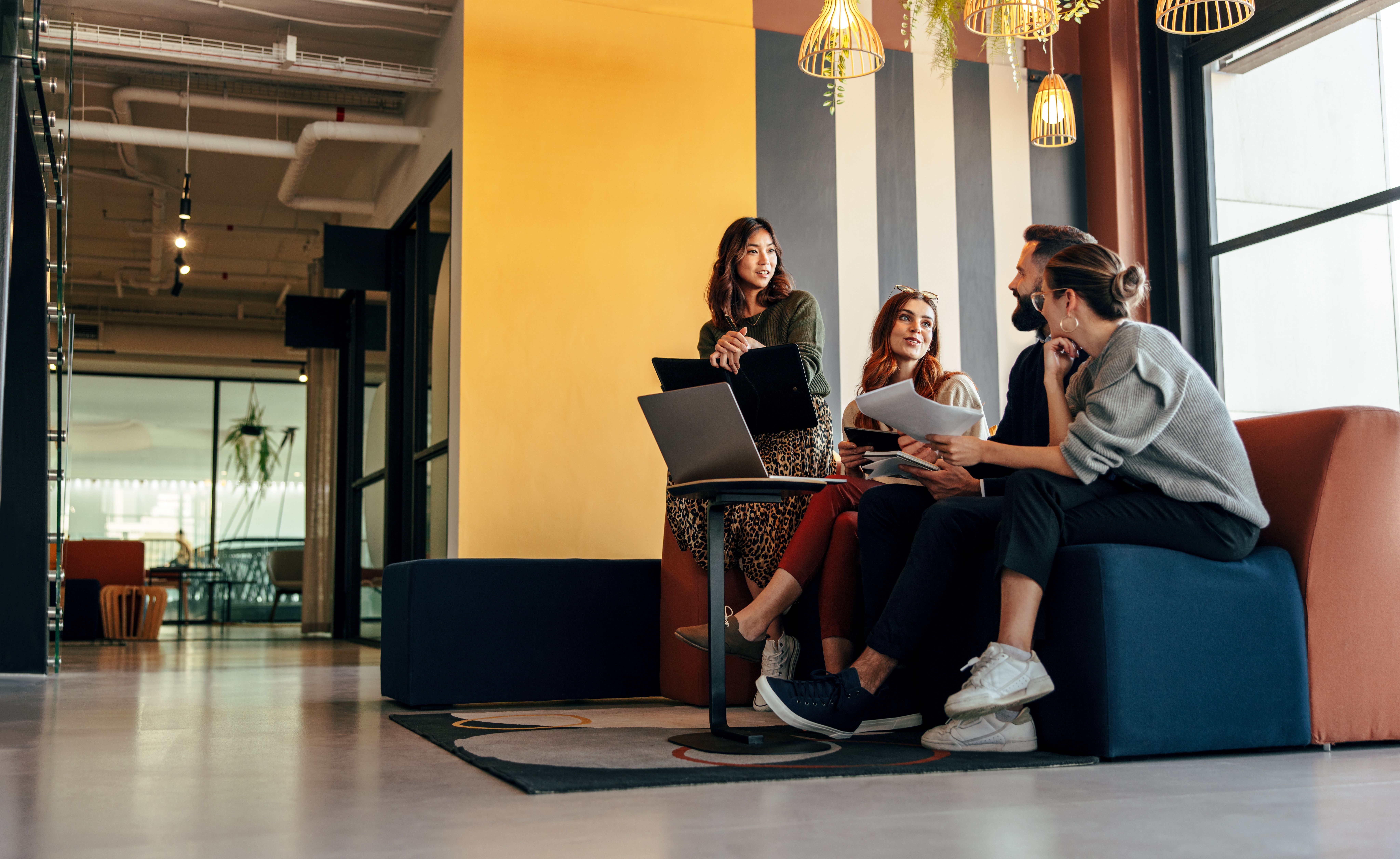 une équipe se réunit dans un petit salon au sein d’un espace de coworking pour une réunion informelle
