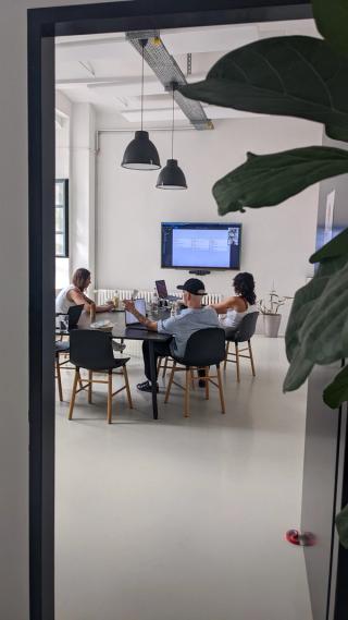 Three designers sitting in a meeting room in front of a screen