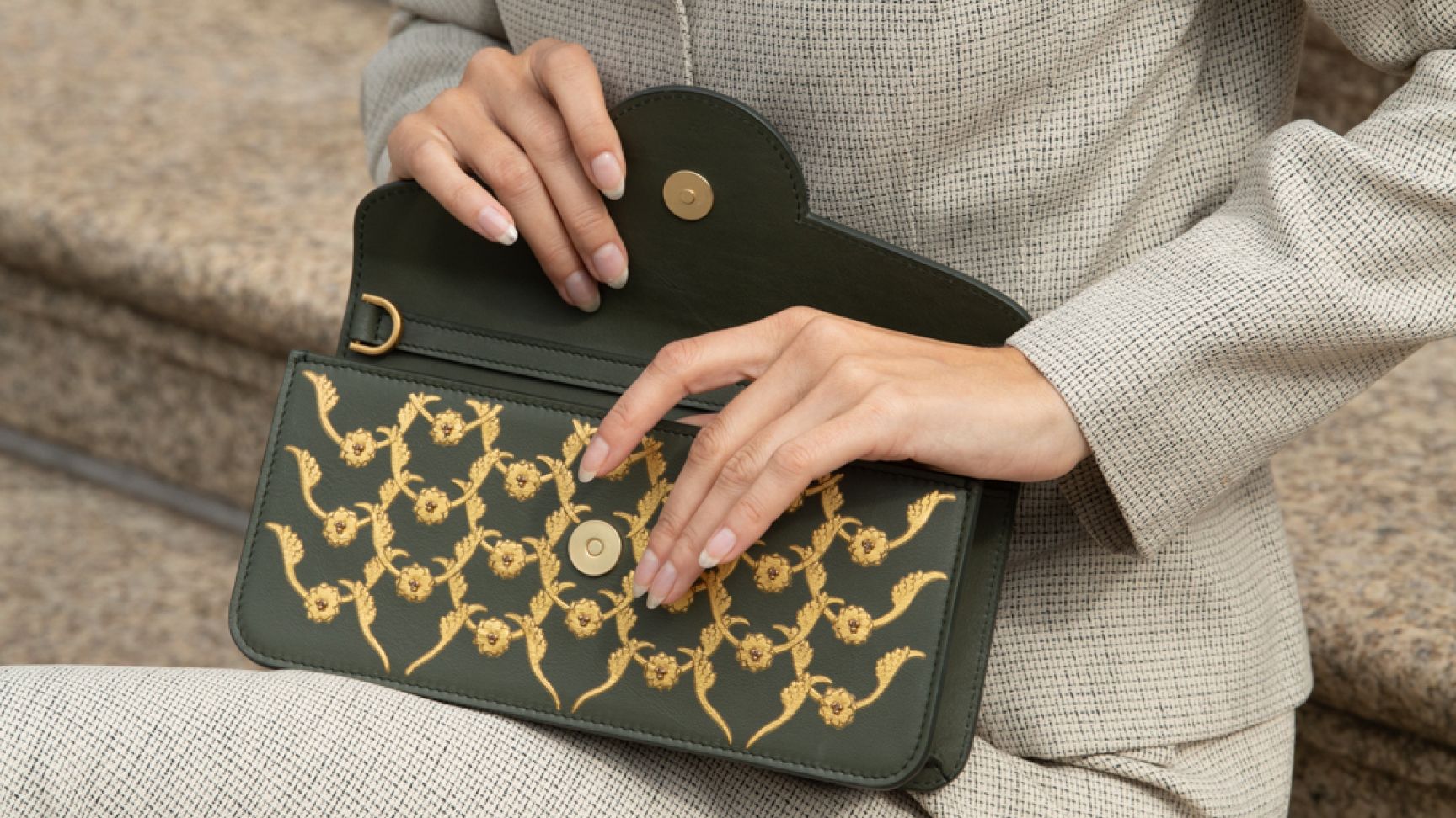 A woman carrying The elegant Charvi clutch featuring gold gilding