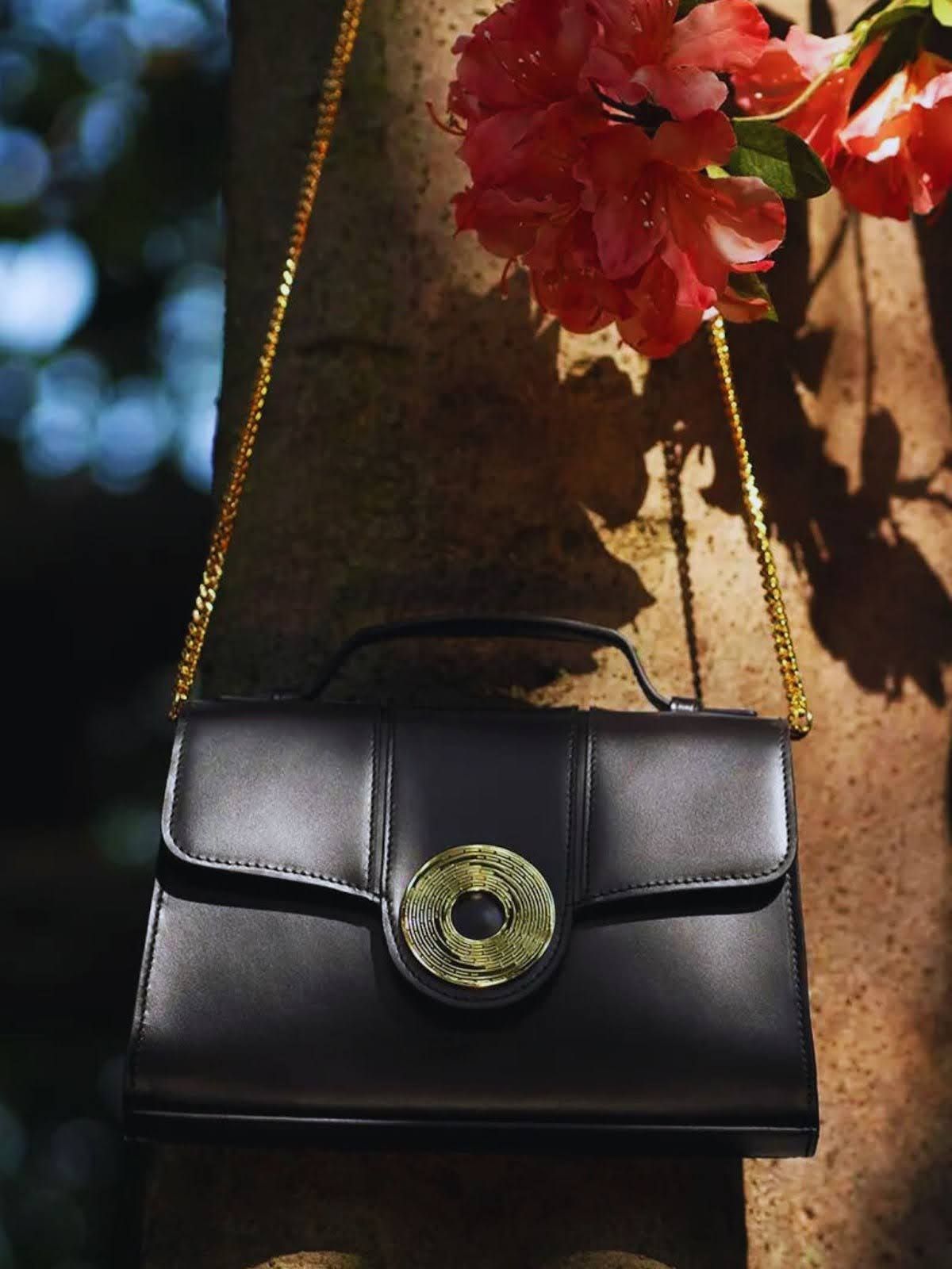 Beautiful Aranyani Aella Monogram Clutch in Obsidian shade with a tree and flower in the background